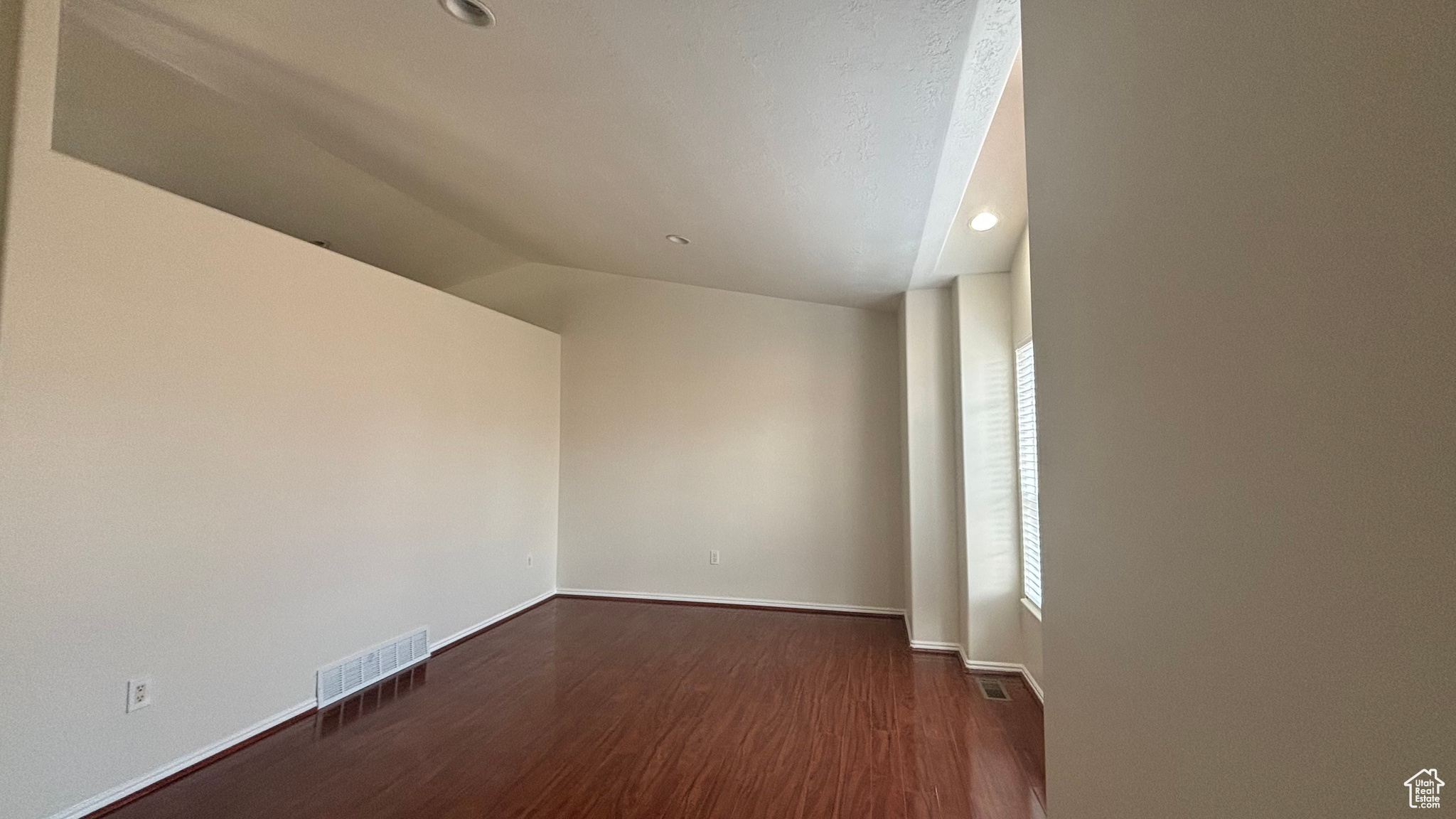 Unfurnished room featuring dark hardwood / wood-style flooring and vaulted ceiling