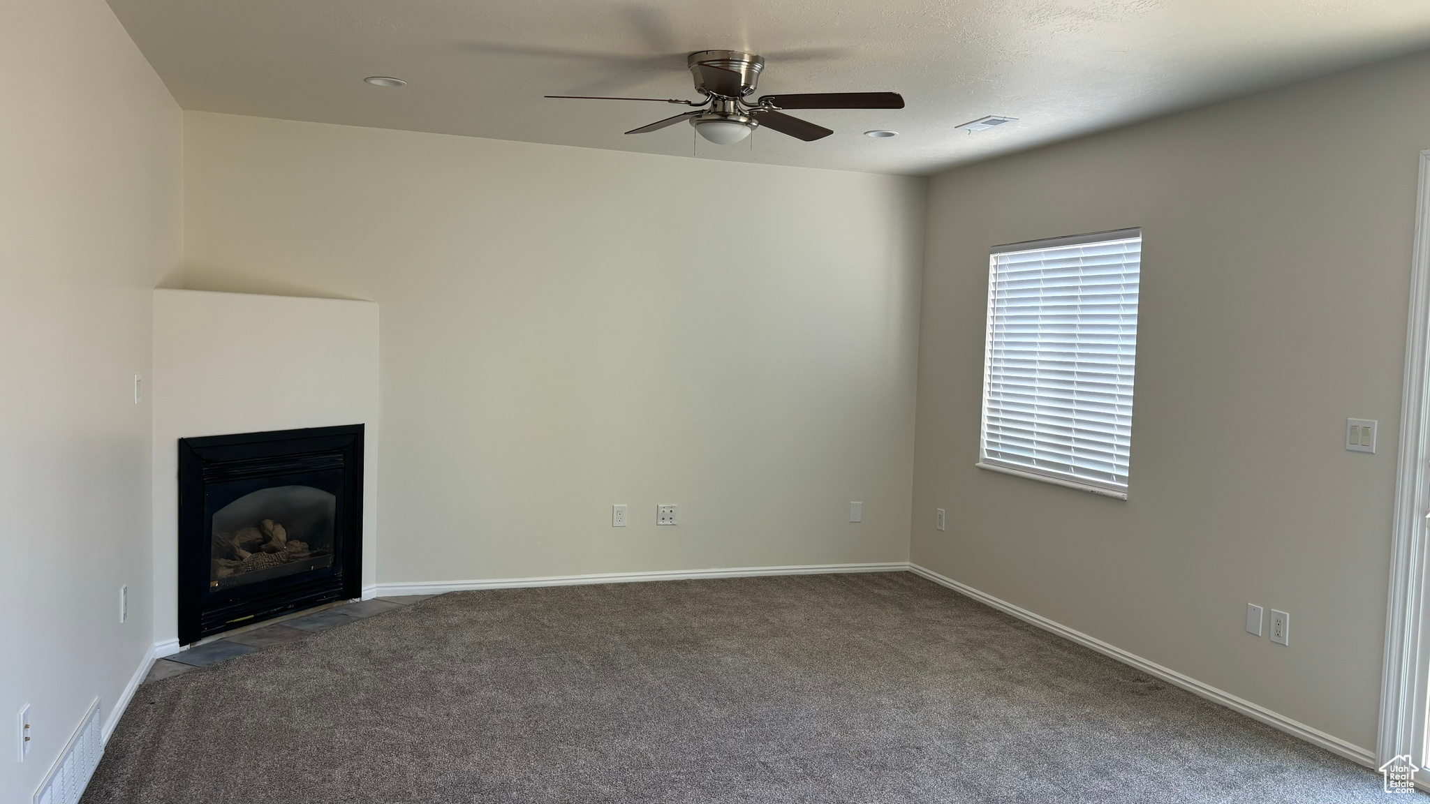 Unfurnished living room featuring carpet flooring and ceiling fan