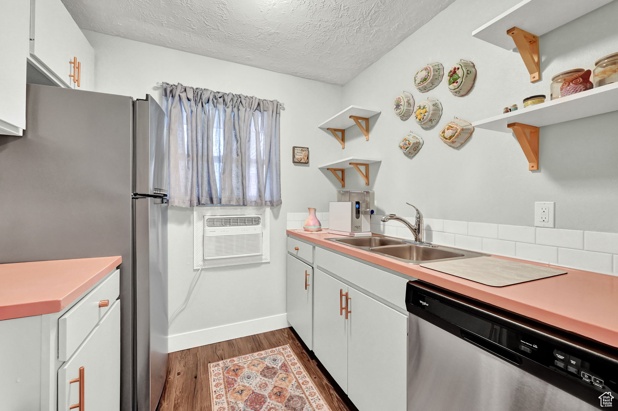 Kitchen with dark hardwood / wood-style flooring, stainless steel appliances, sink, and white cabinets