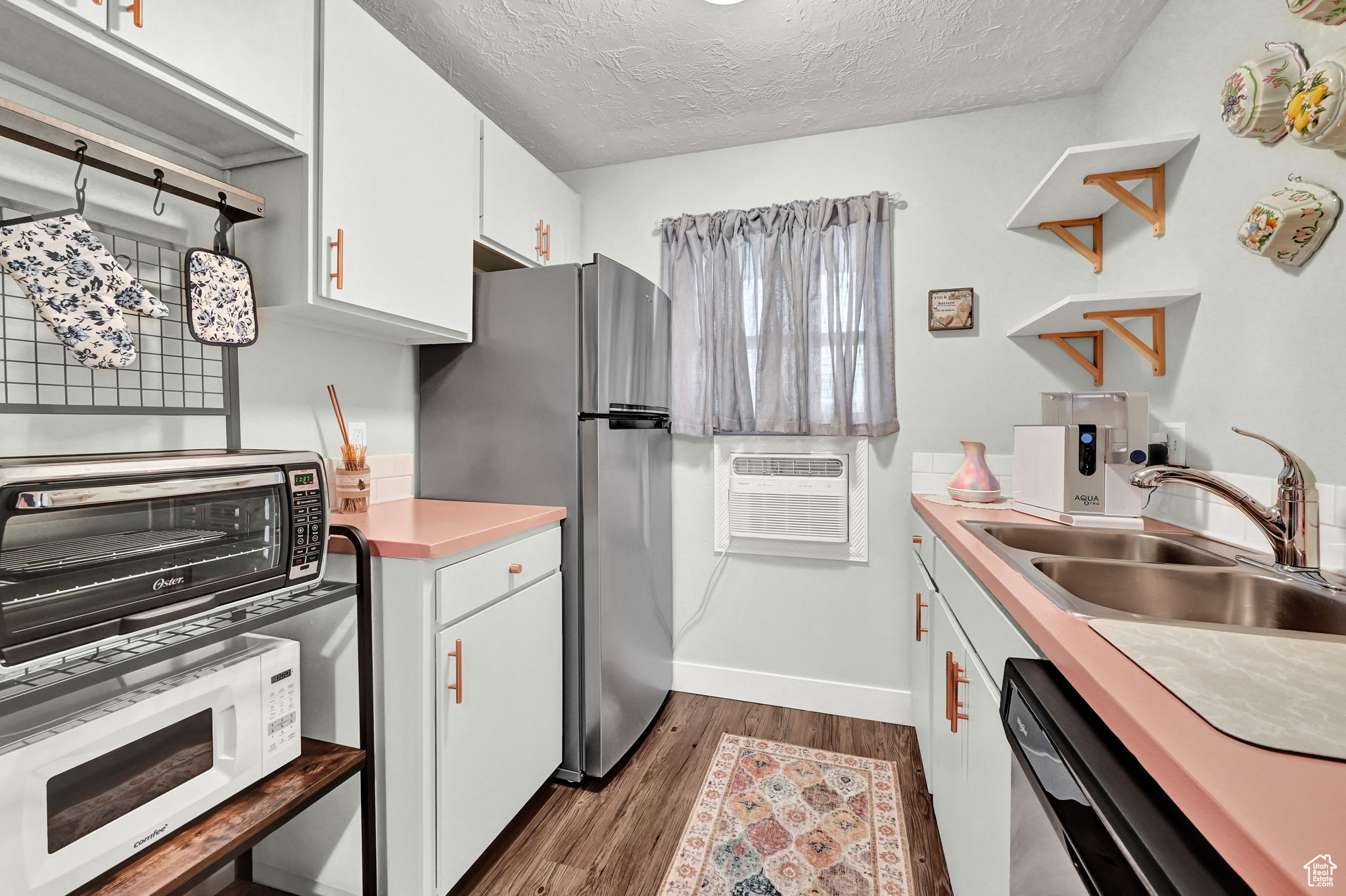 Kitchen with white cabinetry, a textured ceiling, stainless steel appliances, dark hardwood / wood-style flooring, and sink