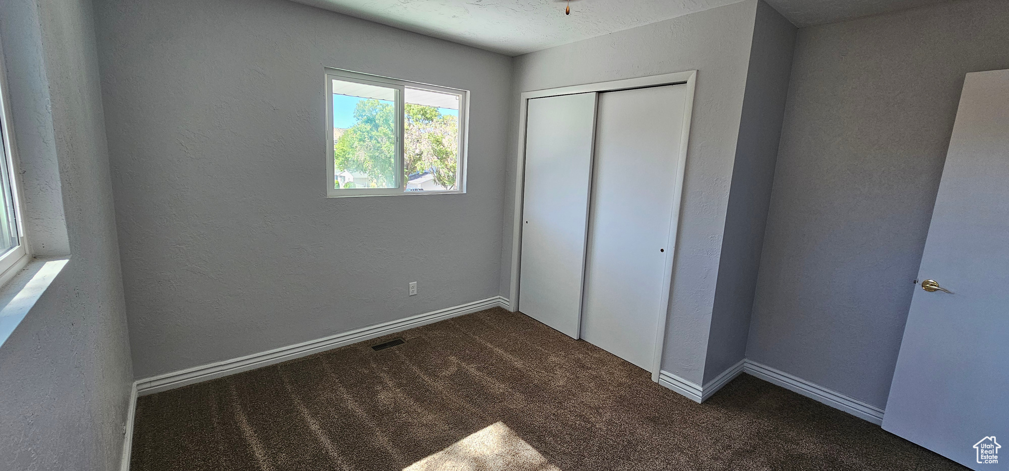 Unfurnished bedroom featuring dark carpet and a closet