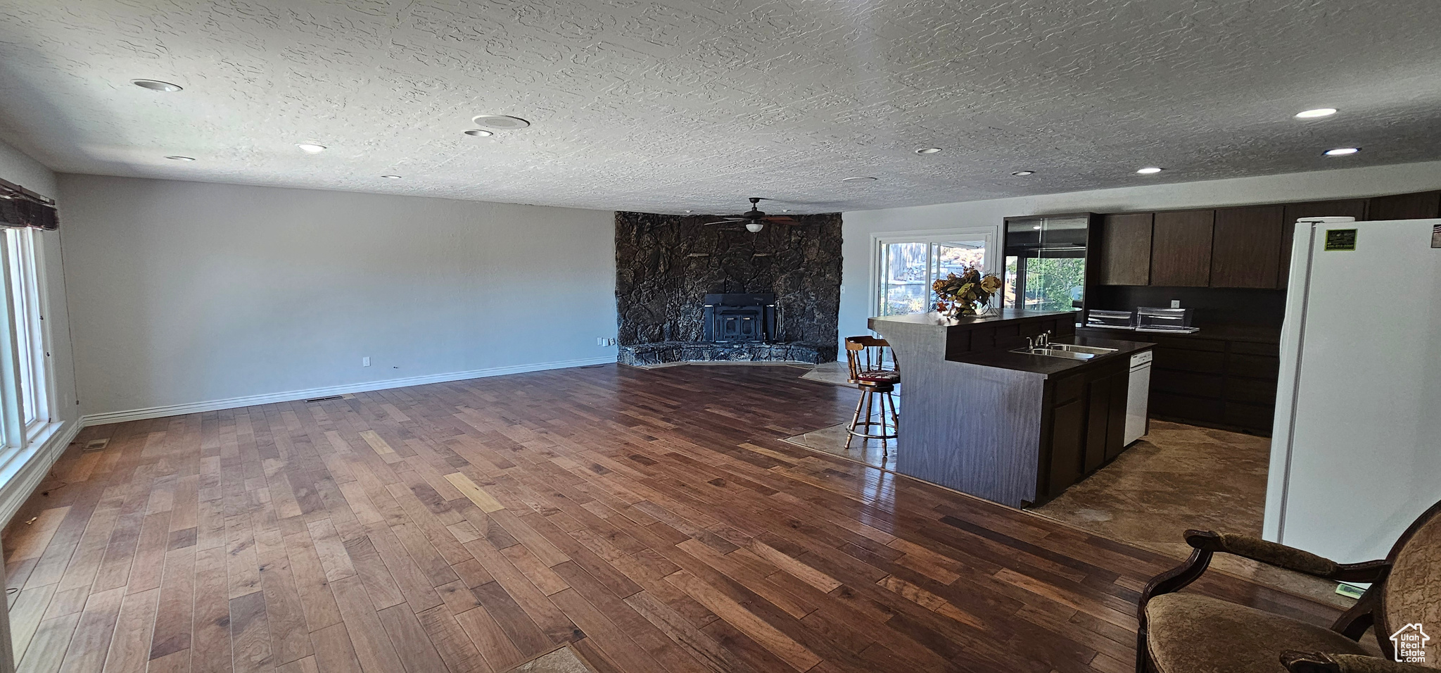 Kitchen with dark brown cabinetry, ceiling fan, a premium fireplace, white fridge, and dark hardwood / wood-style flooring