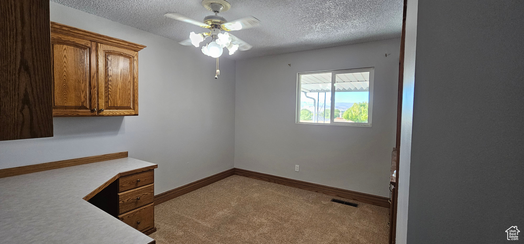 Home office featuring a textured ceiling, ceiling fan, and light colored carpet