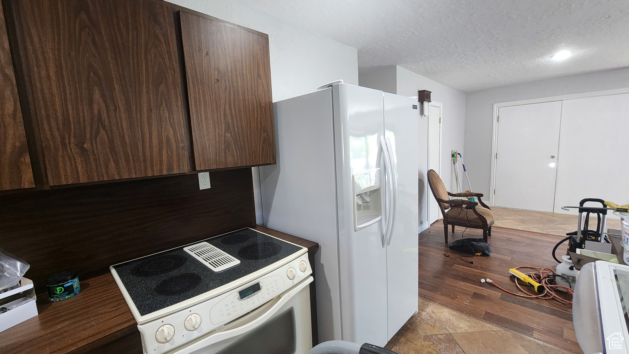 Kitchen with a textured ceiling, white appliances, and light wood-type flooring