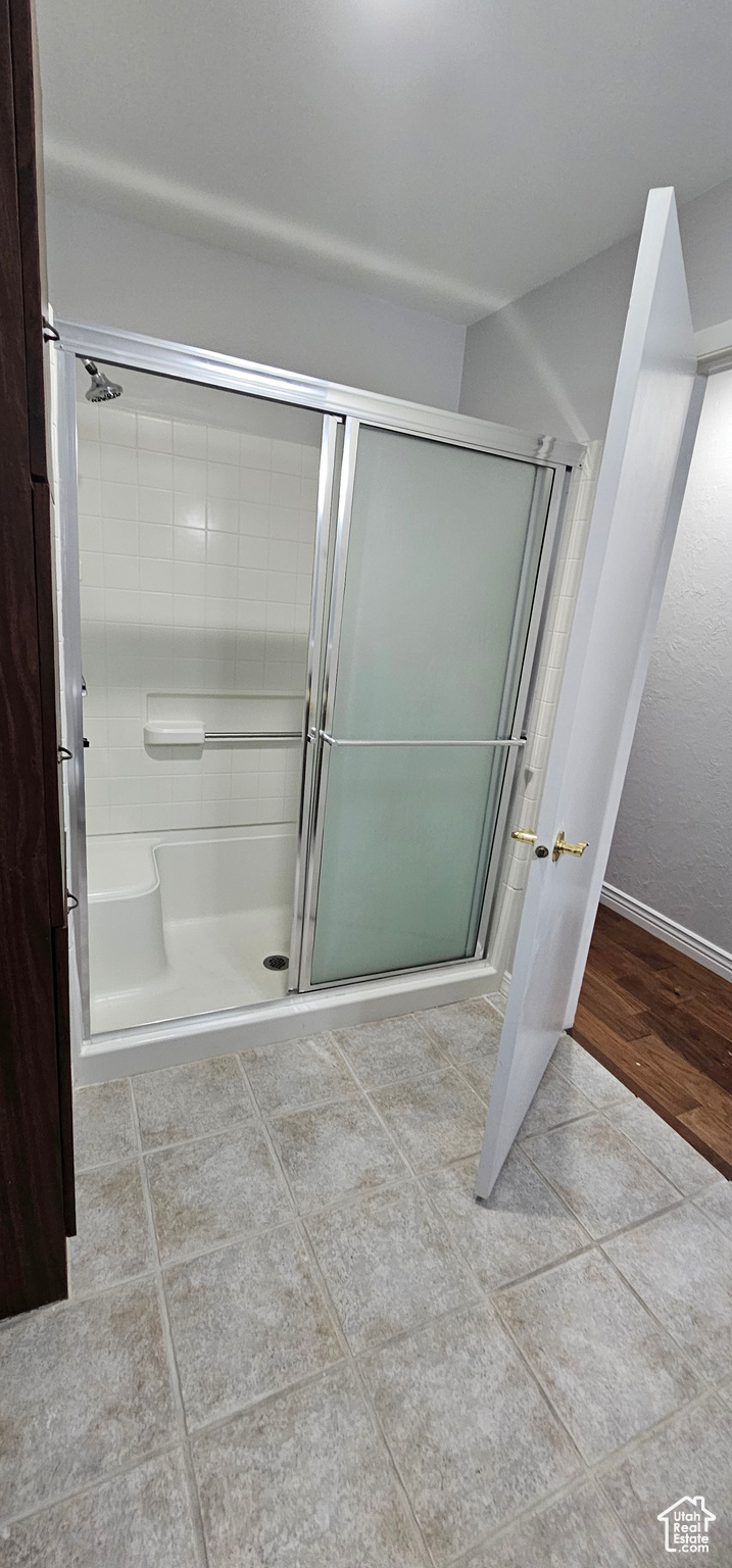 Bathroom with a shower with shower door and tile patterned floors