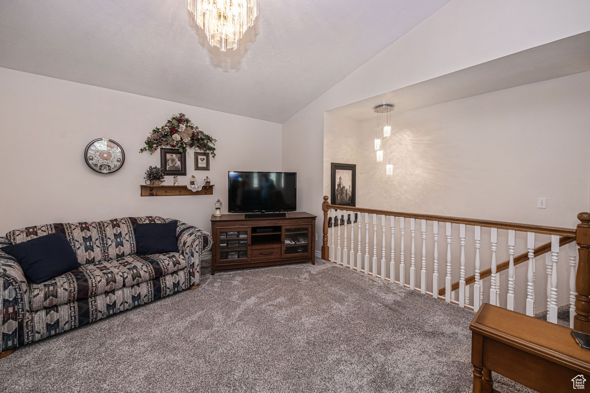 Carpeted living room featuring lofted ceiling and a chandelier