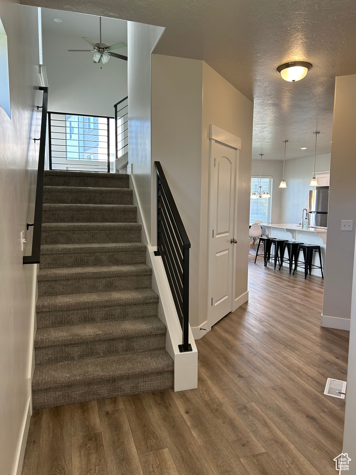 Welcoming entry, carpeted stairs with LVP wood style flooring, ceiling fan in family room.