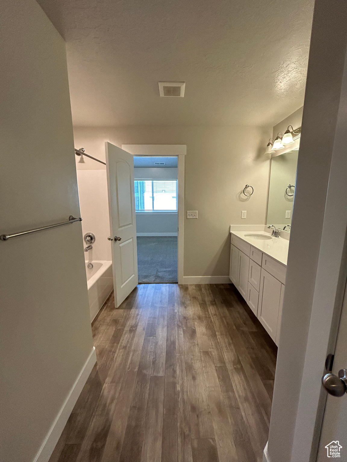 Bathroom featuring a bathtub, wood-style flooring, a textured ceiling, and double vanity.