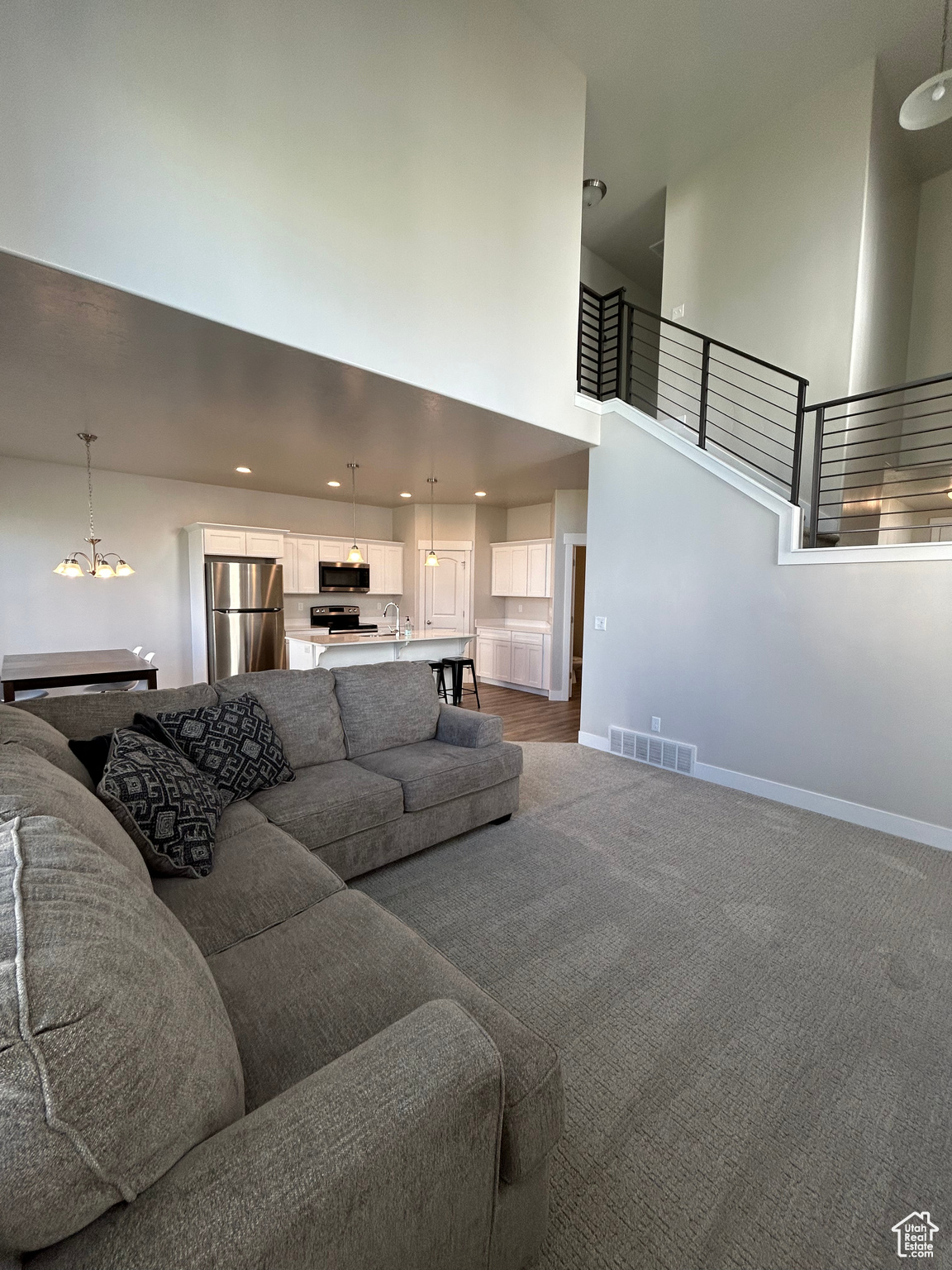 Carpeted living room with vaulted ceiling, and large ceiling fan.