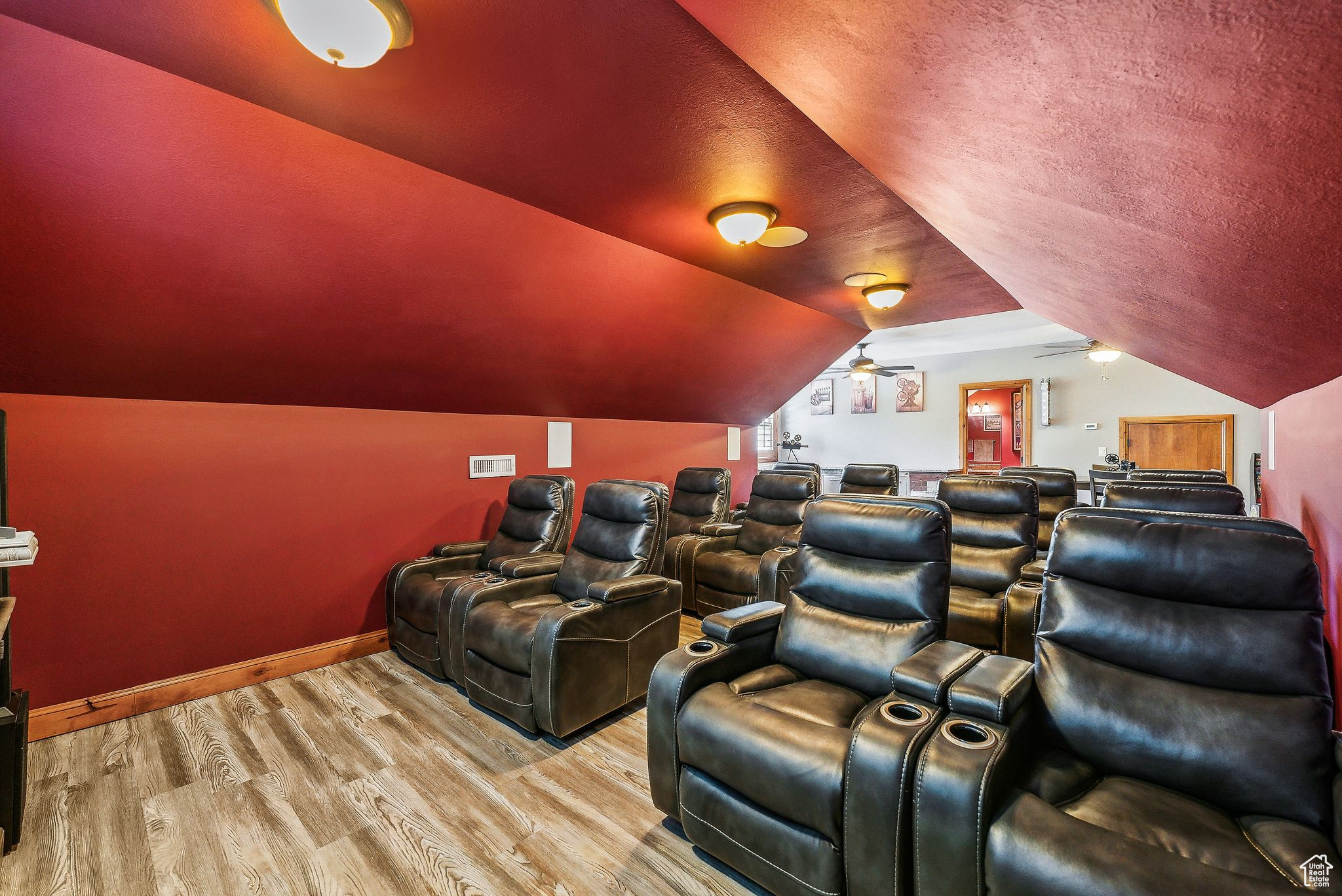 Home theater room with hardwood / wood-style floors, ceiling fan, and vaulted ceiling