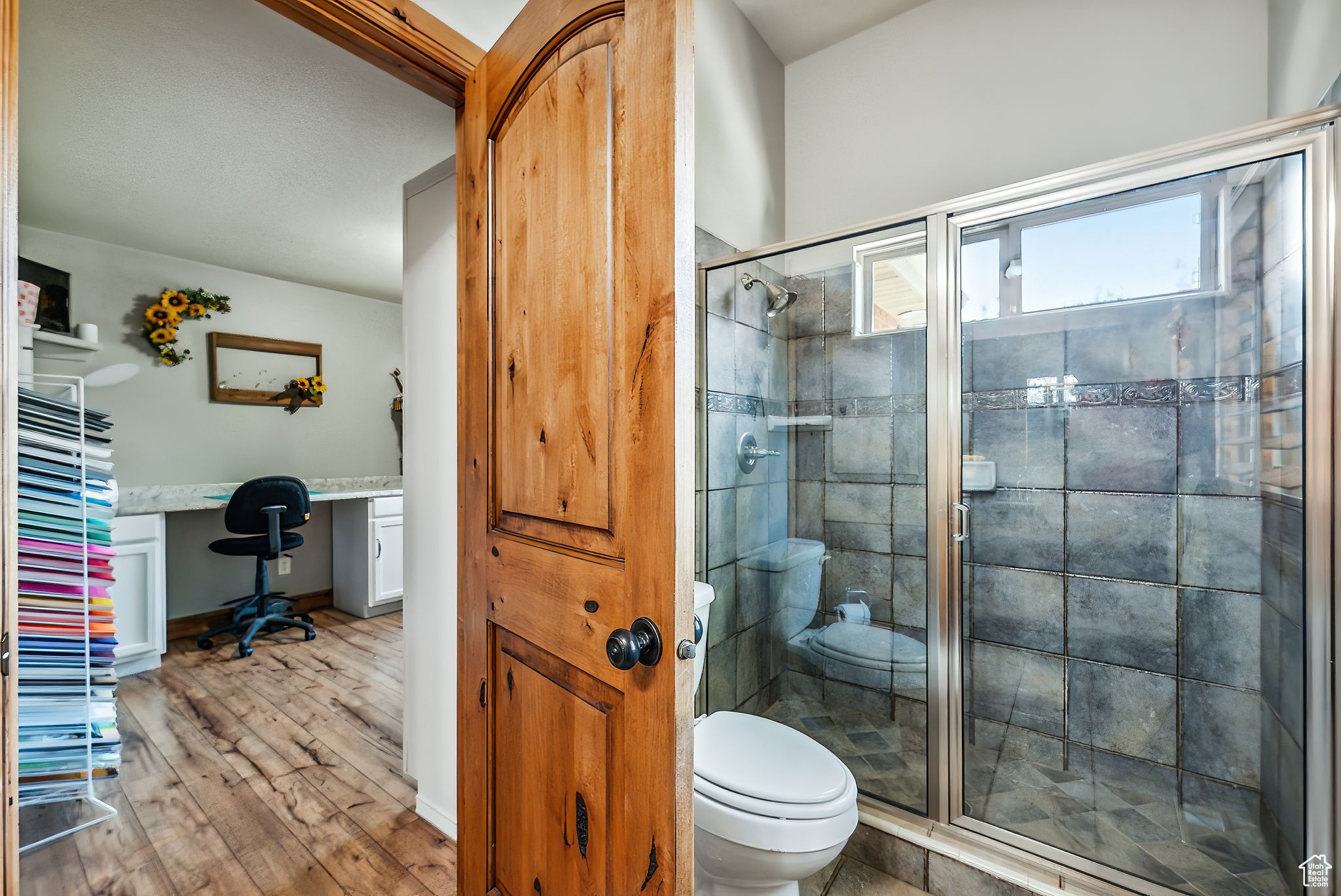 Bathroom with toilet, hardwood / wood-style flooring, and a shower with door