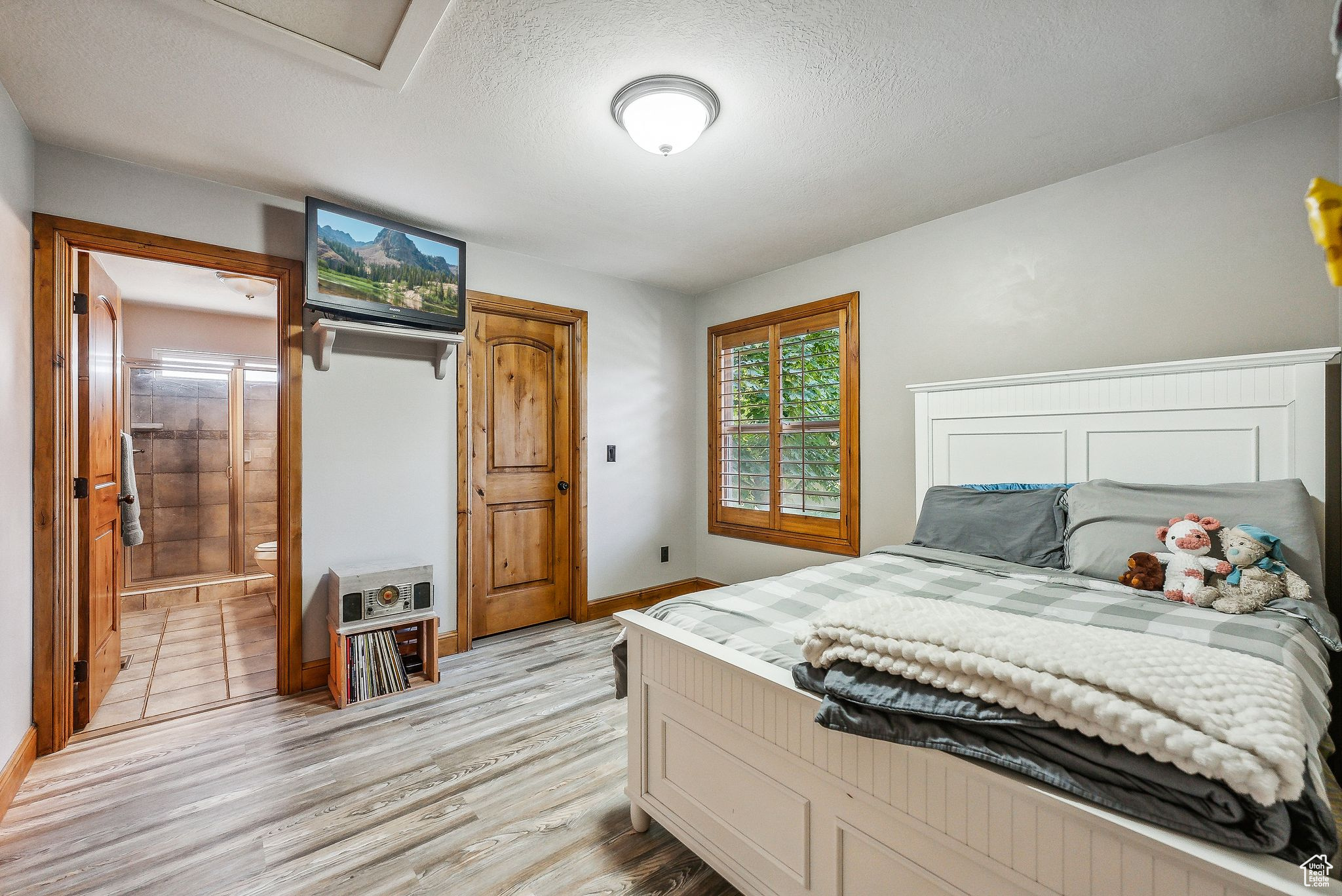 Bedroom with light wood-type flooring, connected bathroom, and a textured ceiling