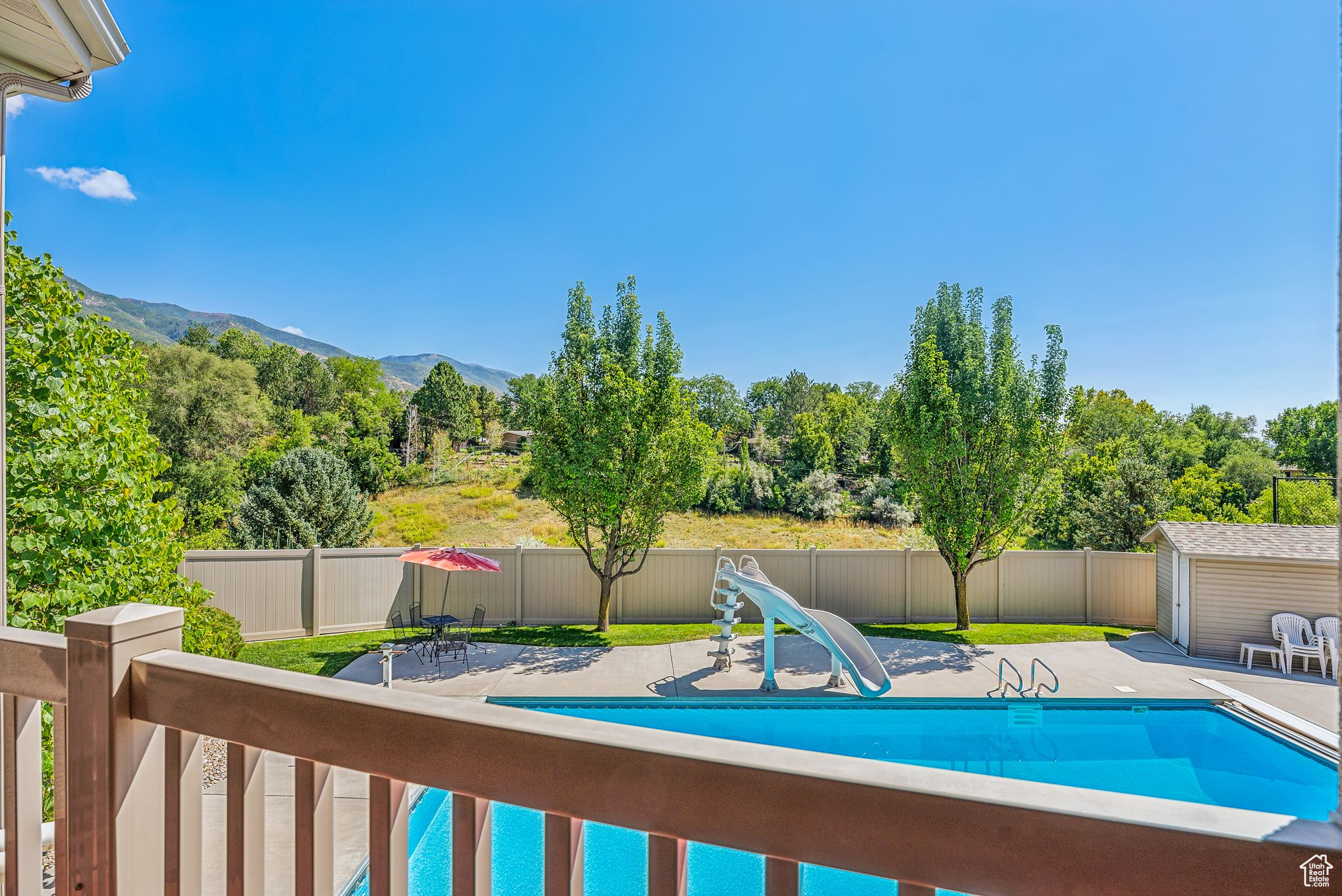 View of pool featuring a mountain view, a water slide, an outbuilding, and a patio