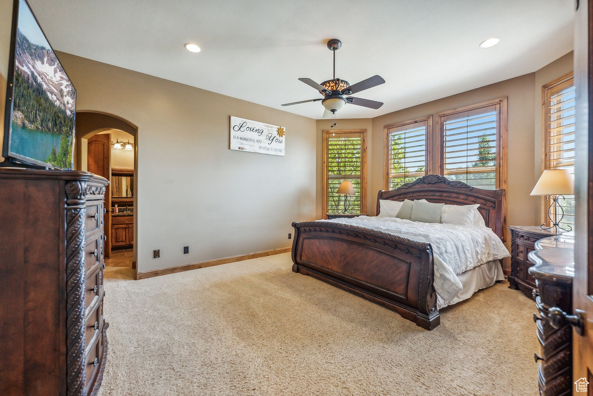 Bedroom with light colored carpet, ensuite bathroom, and ceiling fan