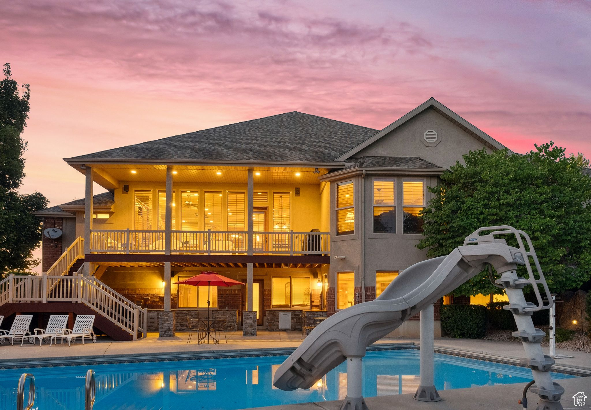 Pool at dusk featuring a water slide and a patio