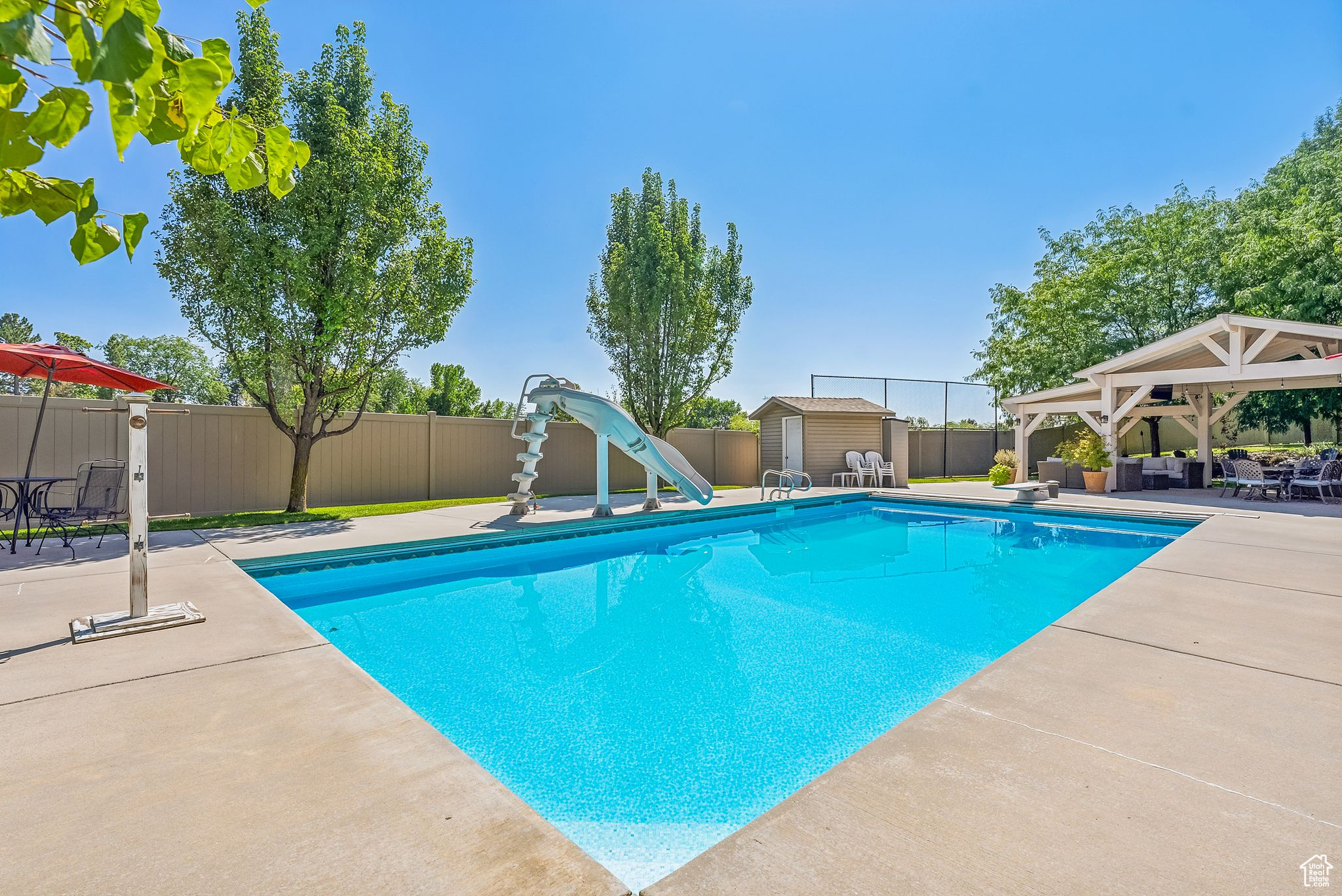 View of pool with an outbuilding, a gazebo, a water slide, a diving board, and a patio