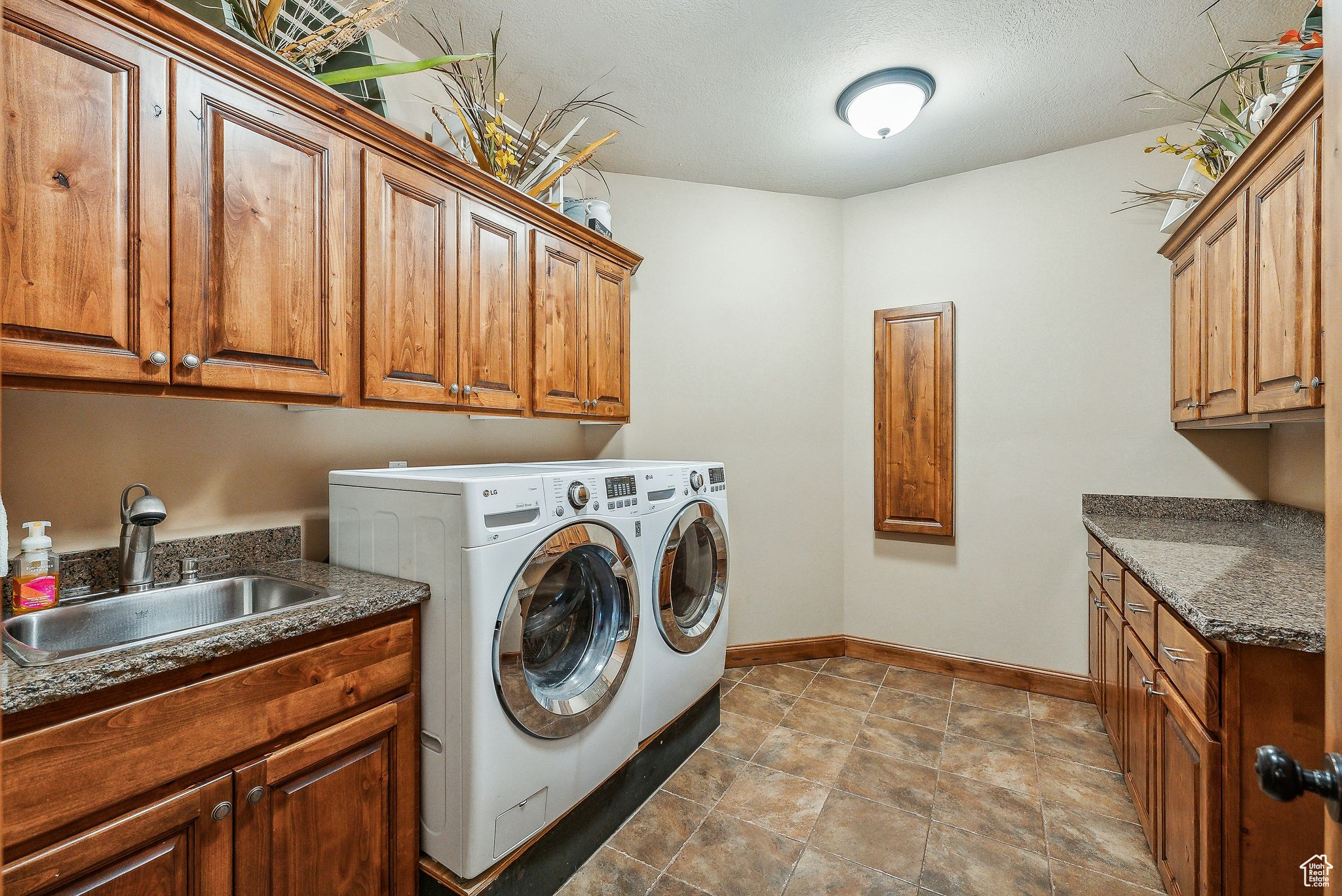 Washroom featuring separate washer and dryer, light tile patterned floors, cabinets, and sink