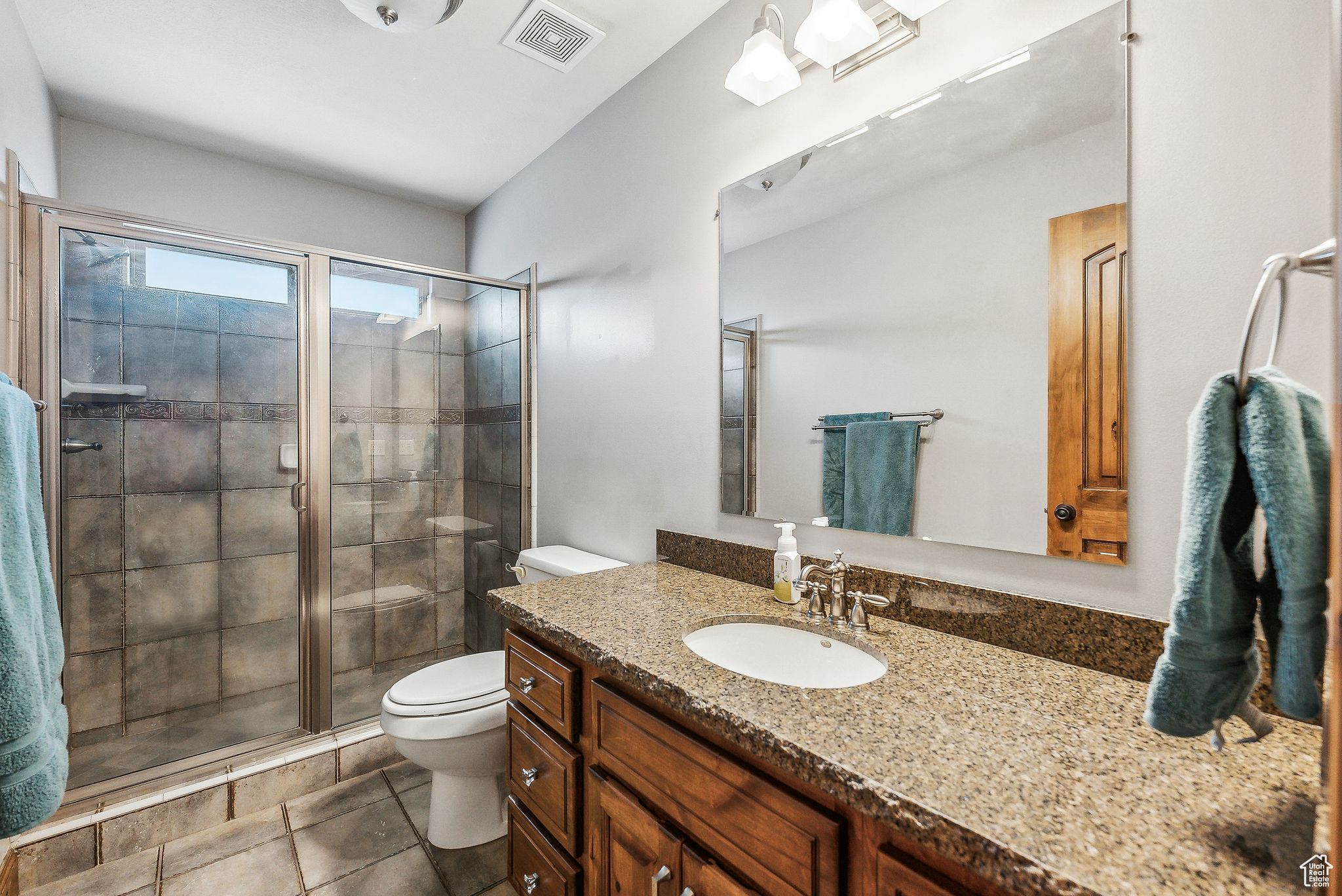 Bathroom featuring an enclosed shower, tile patterned flooring, toilet, and vanity