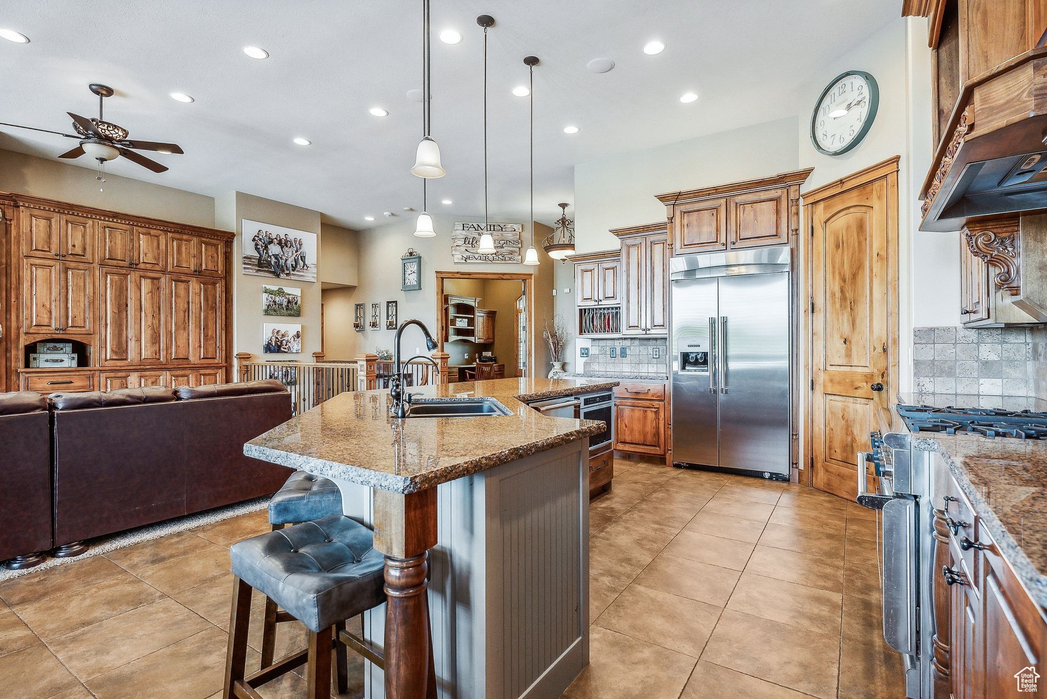 Kitchen with a kitchen island with sink, high quality appliances, tasteful backsplash, a kitchen bar, and light stone counters