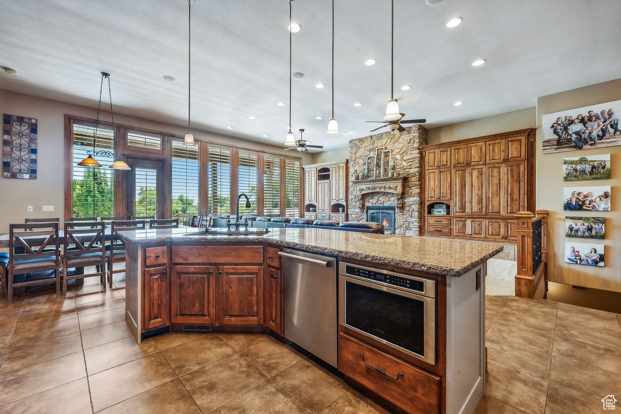 Kitchen featuring a center island with sink, ceiling fan, a wealth of natural light, and light stone countertops