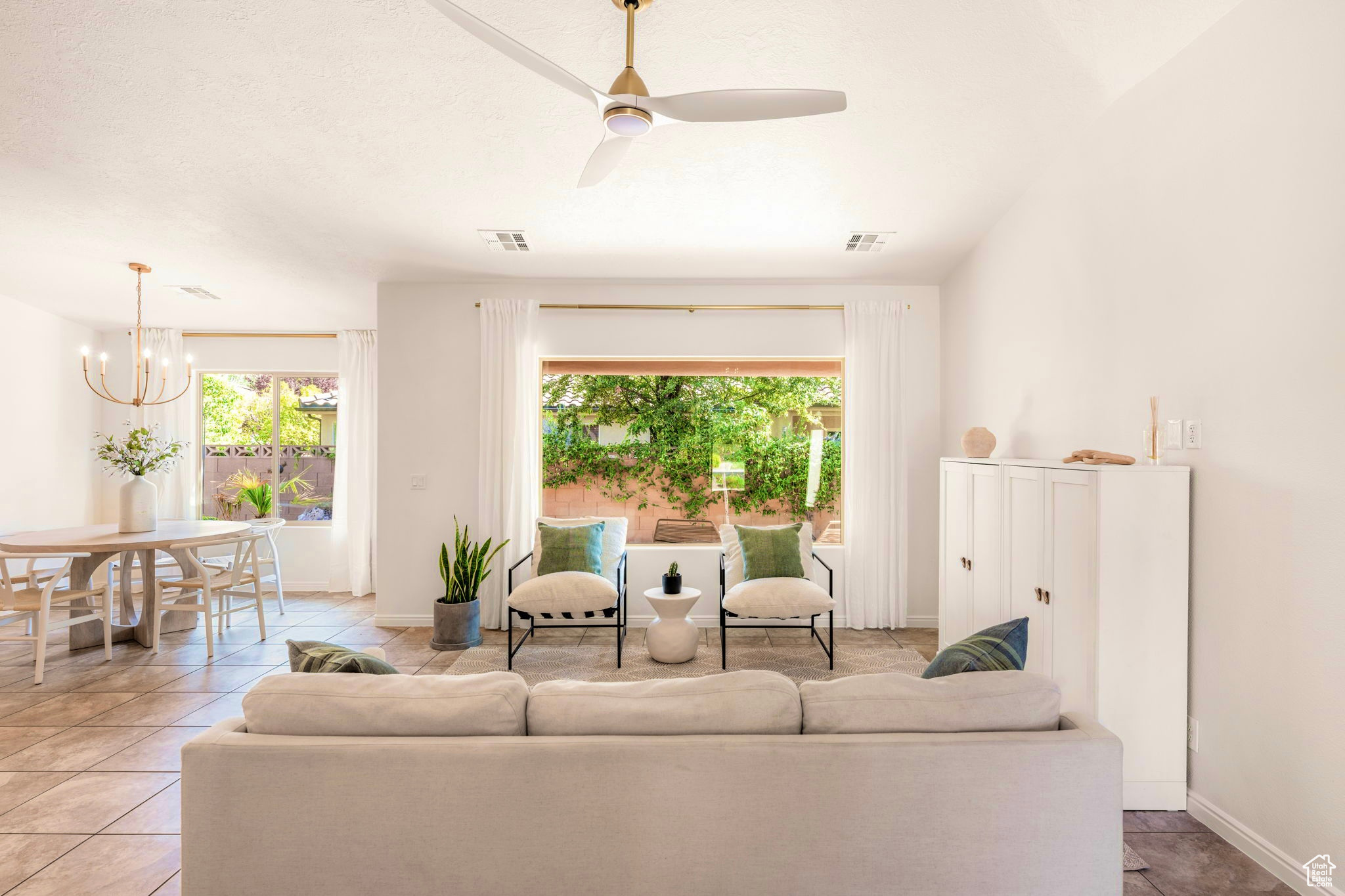 Living room featuring lofted ceiling, ceiling fan with notable chandelier, and light tile patterned floors