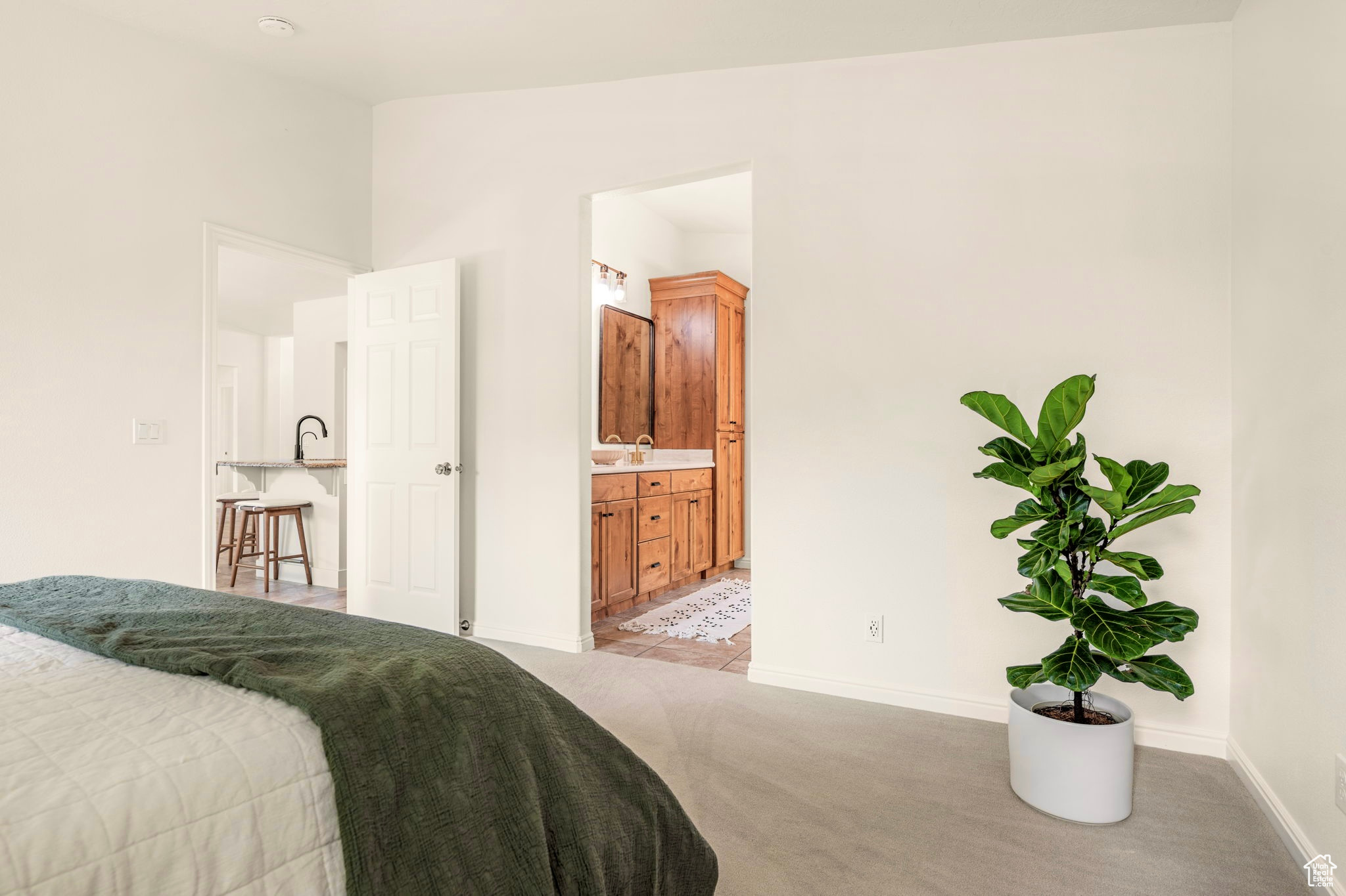 Bedroom with lofted ceiling, connected bathroom, and light carpet