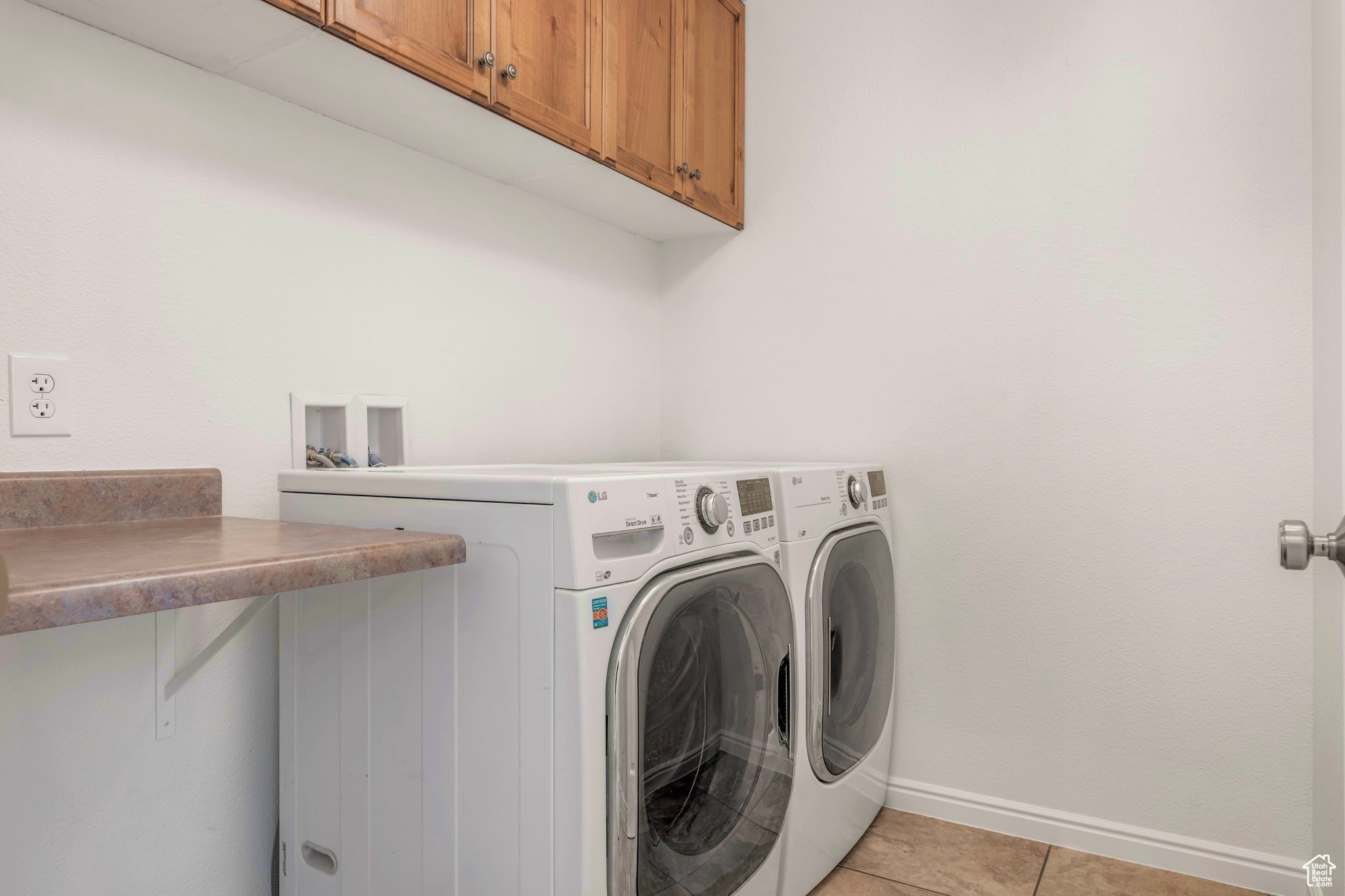 Washroom featuring separate washer and dryer, cabinets, and light tile patterned floors