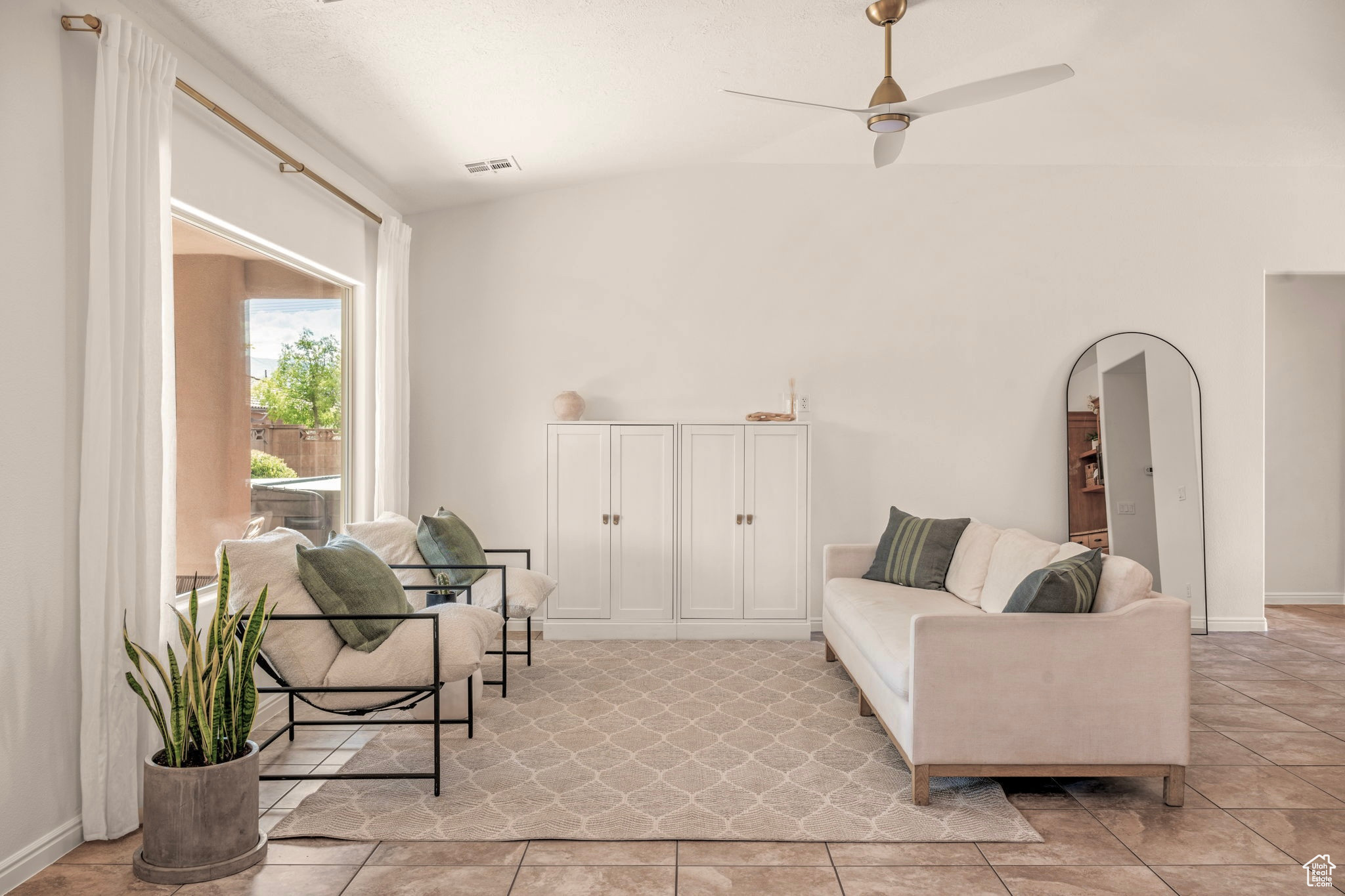 Living room featuring ceiling fan, light tile patterned floors, and vaulted ceiling