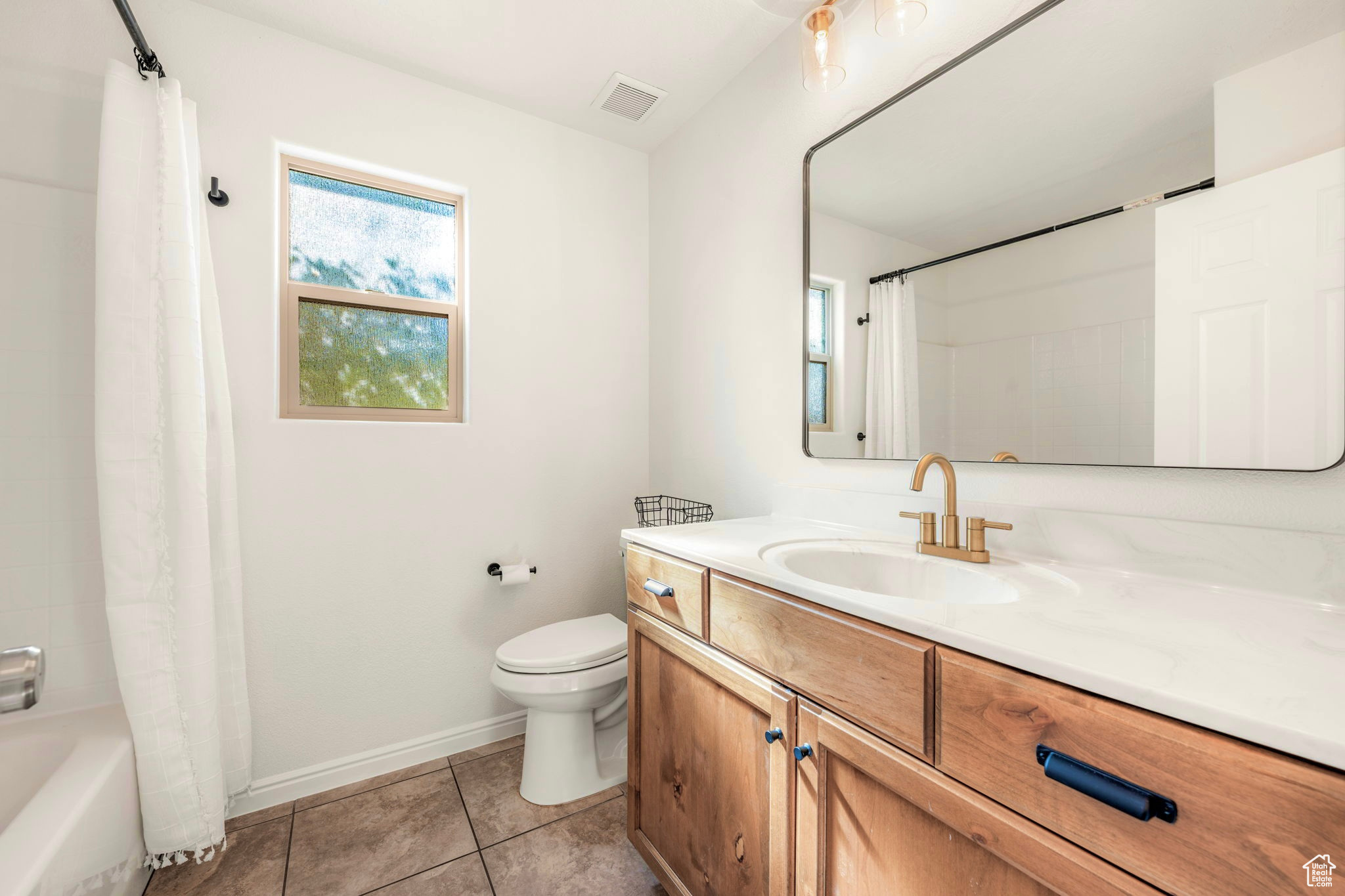 Full bathroom with vanity, toilet, tile patterned floors, and shower / bath combo