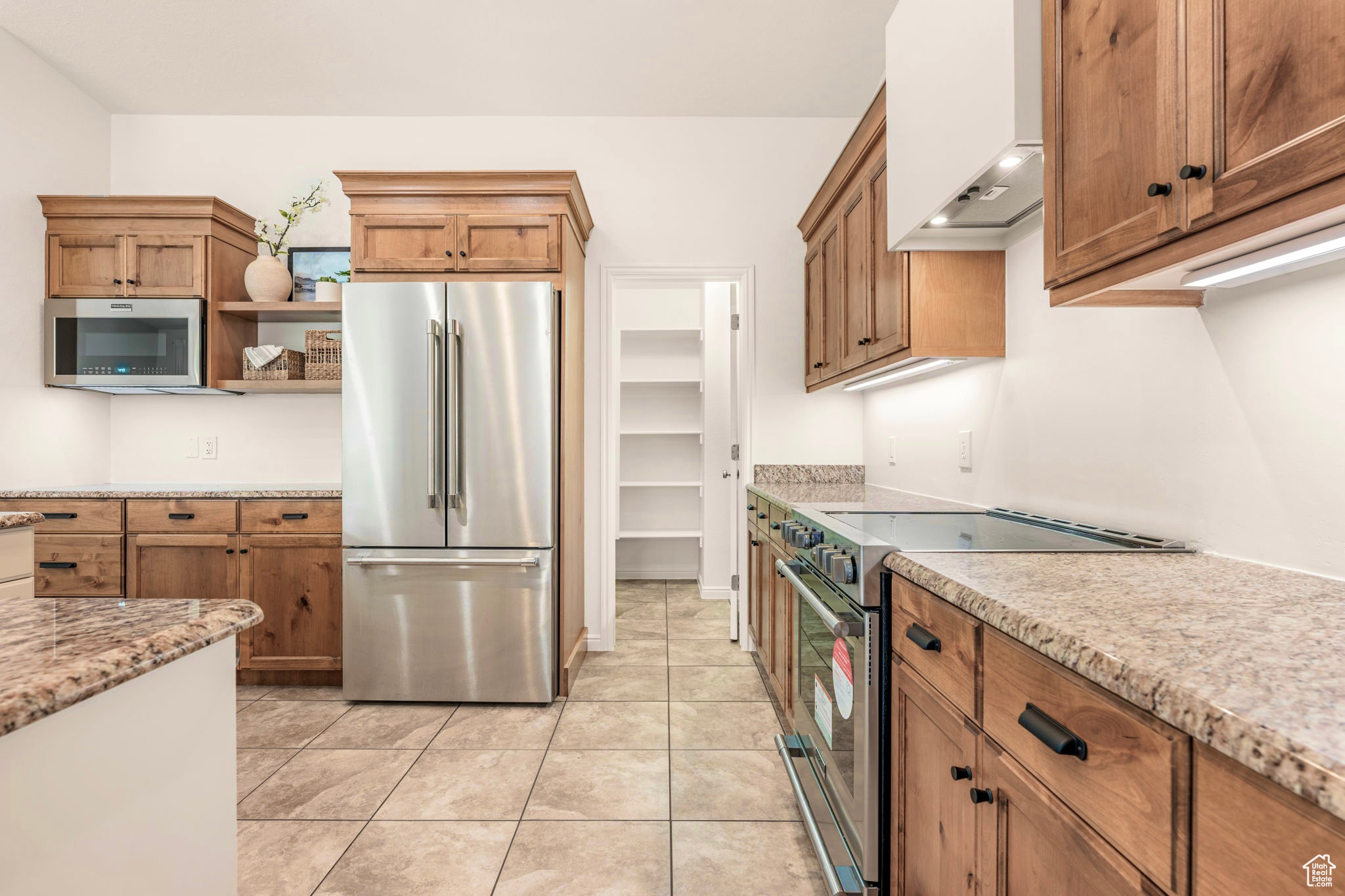 Kitchen featuring light stone counters, stainless steel appliances, light tile patterned flooring, and custom exhaust hood