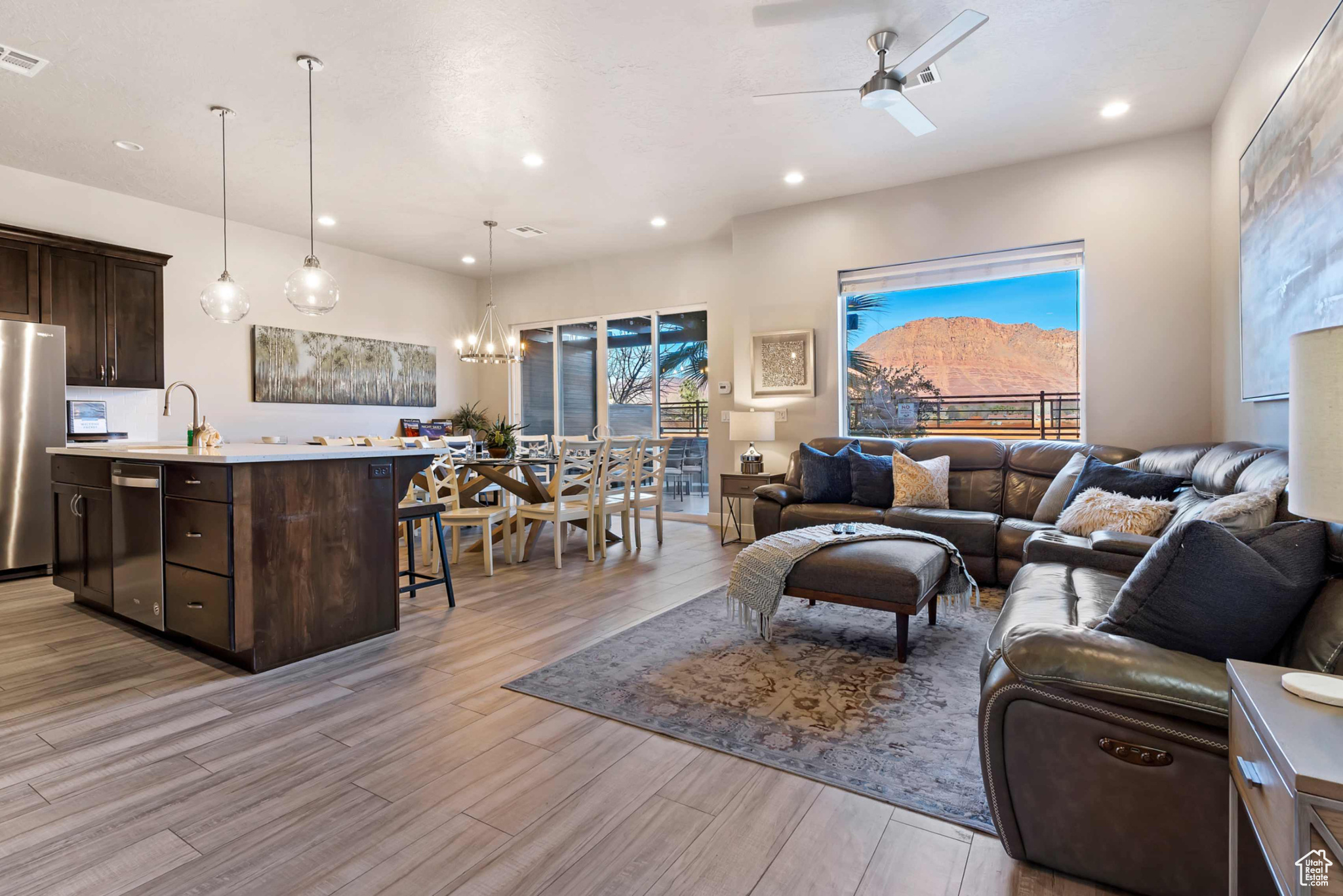 Living room with ceiling fan with notable chandelier, a healthy amount of sunlight, and light wood-type flooring