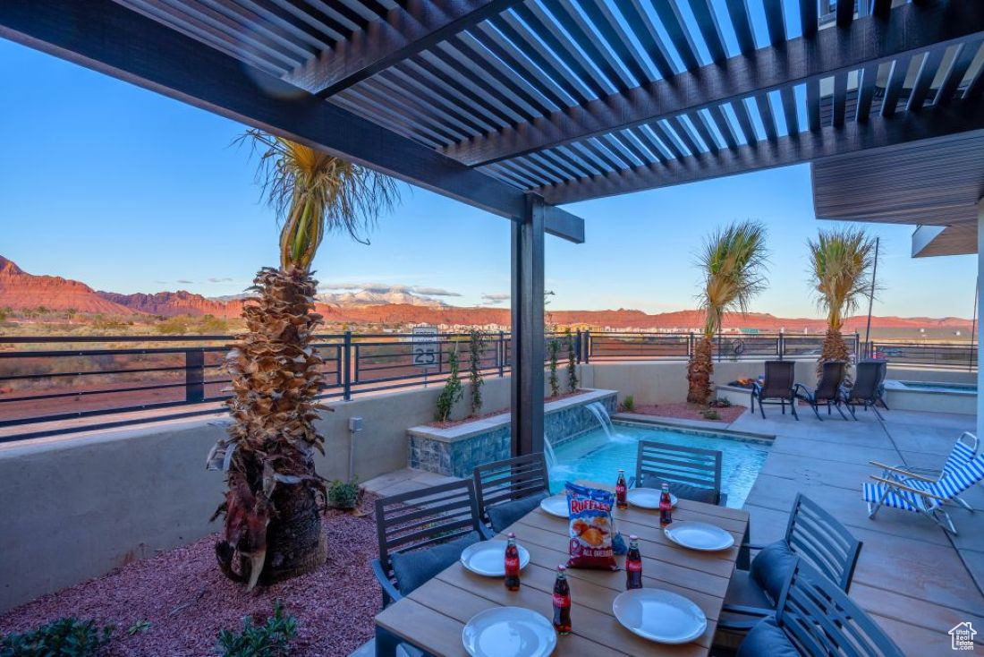 View of patio / terrace with a fenced in pool, a pergola, a mountain view, and pool water feature