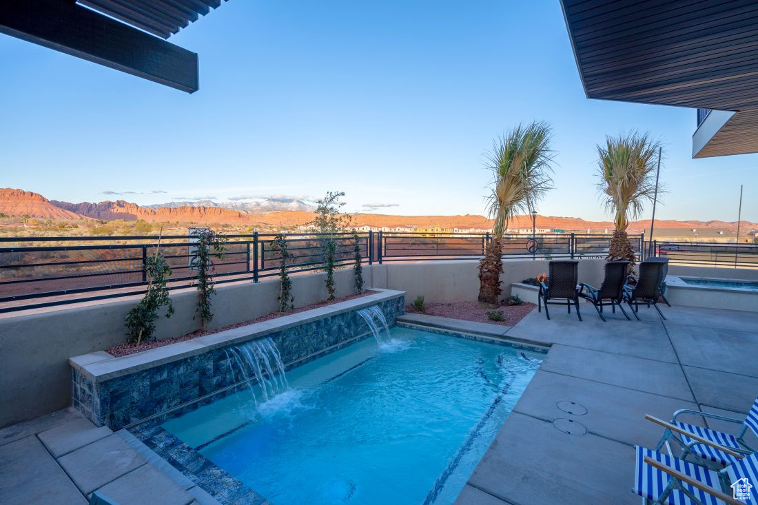 View of pool featuring a mountain view, pool water feature, and a patio