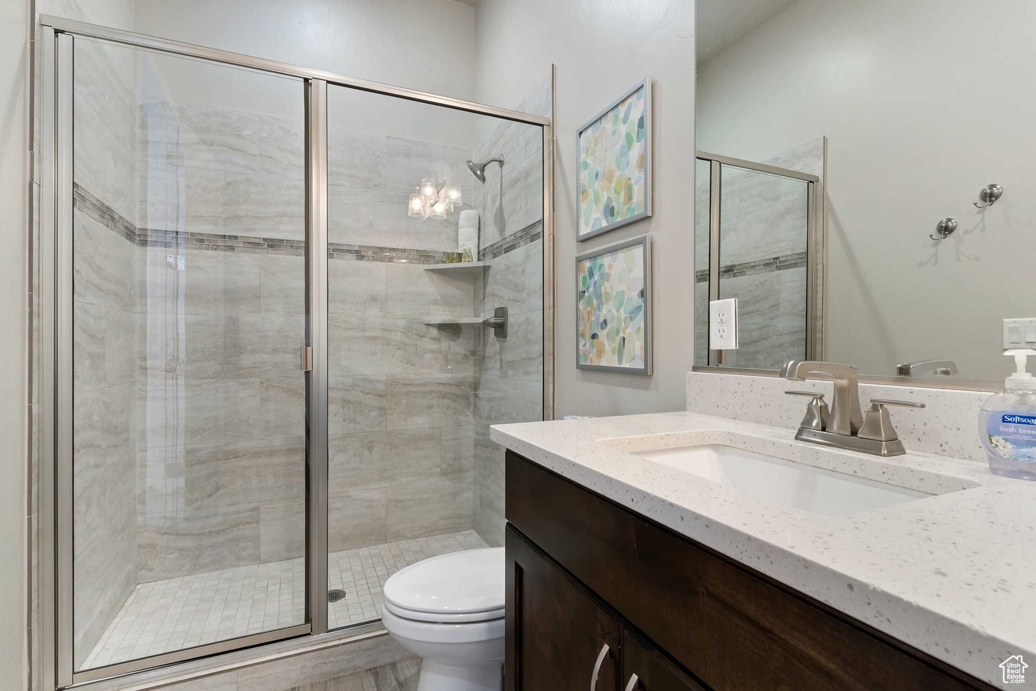 Bathroom featuring toilet, vanity, and a shower with shower door