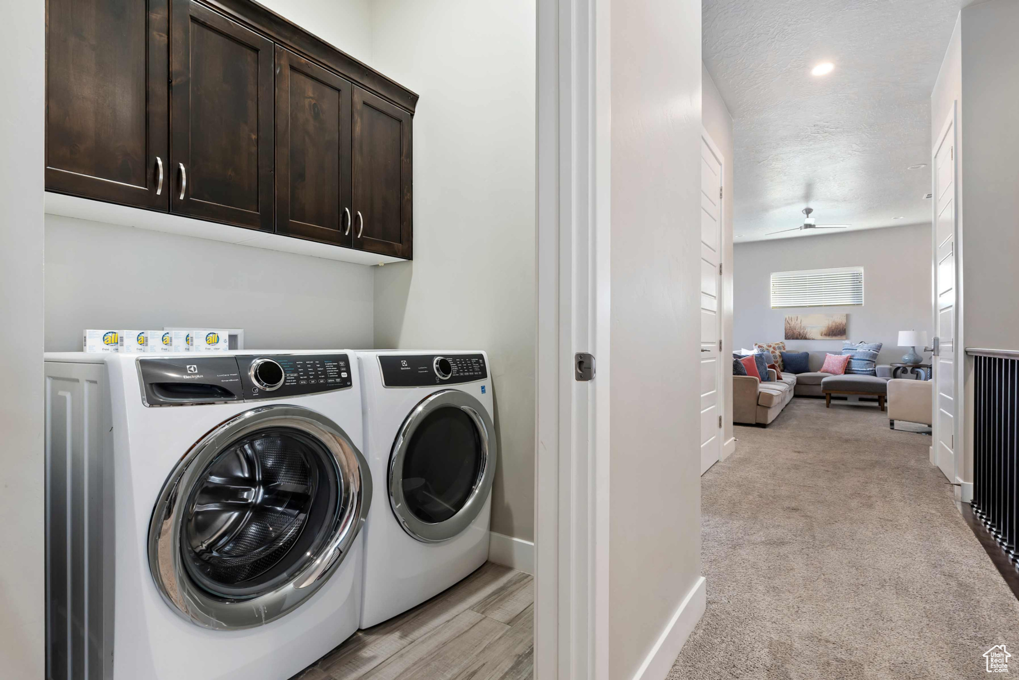 Laundry area featuring cabinets, a textured ceiling, light carpet, ceiling fan, and independent washer and dryer