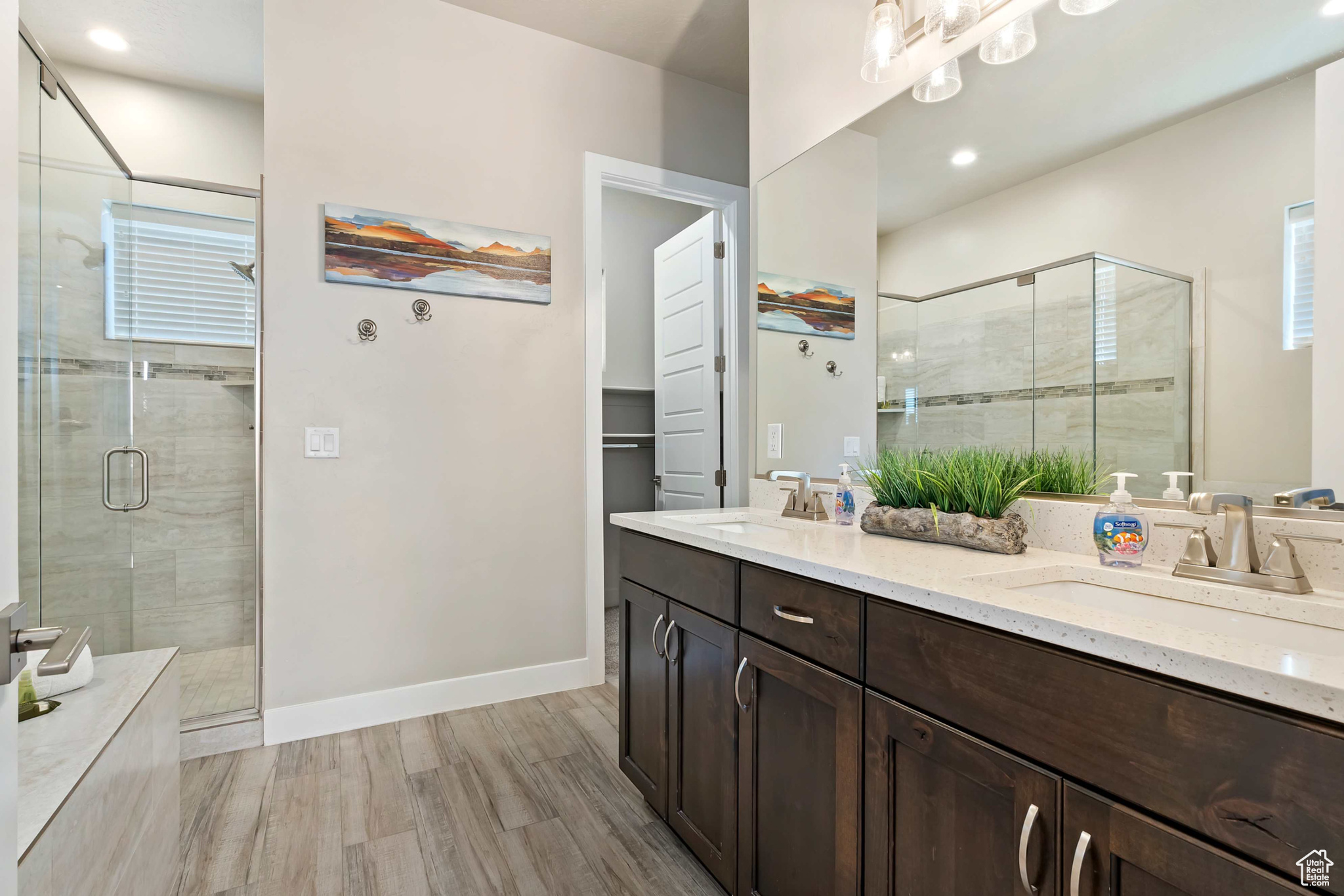 Bathroom featuring a shower with door, double sink vanity, and wood-type flooring