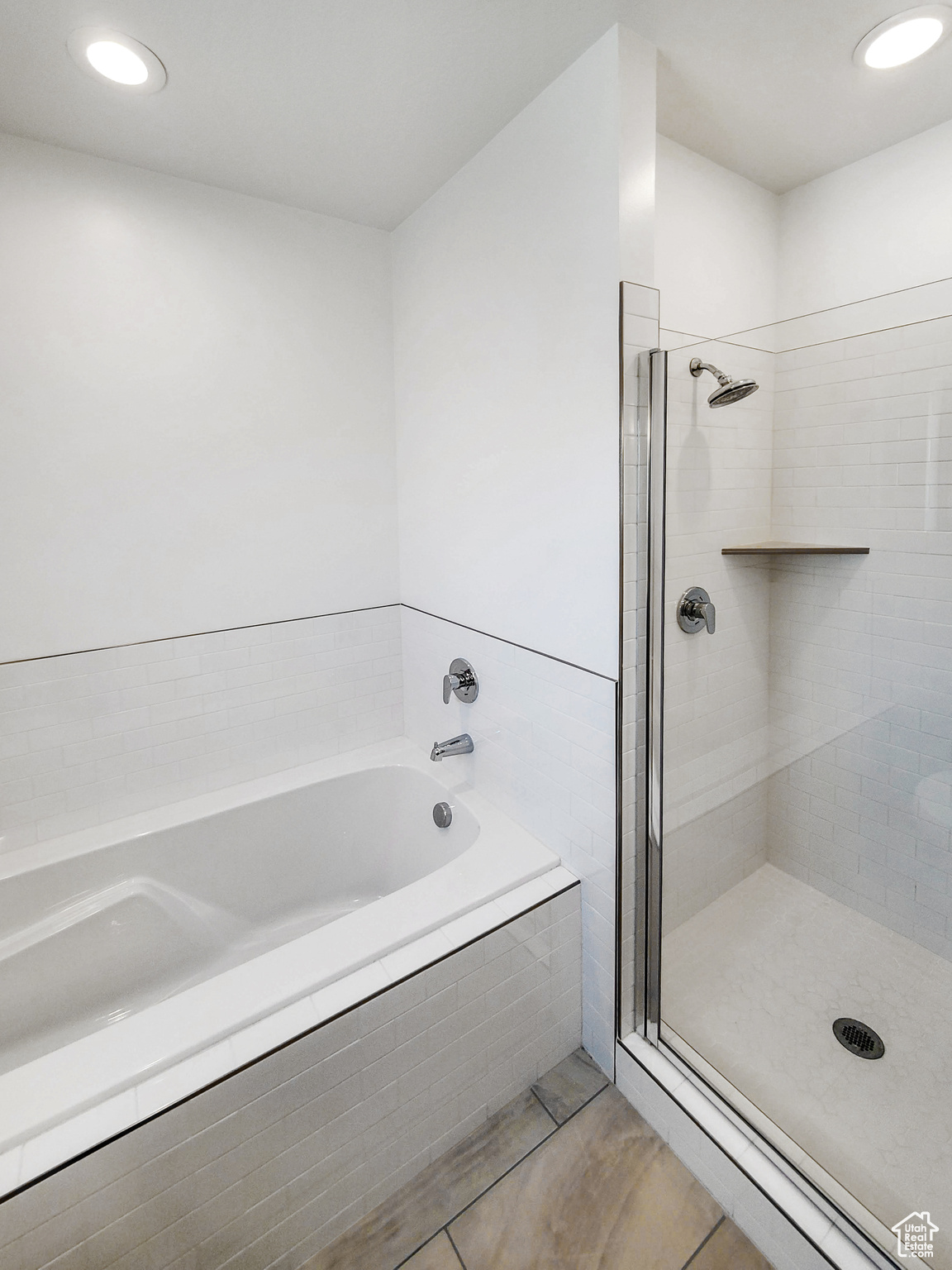 Bathroom with shower with separate bathtub and tile patterned floors