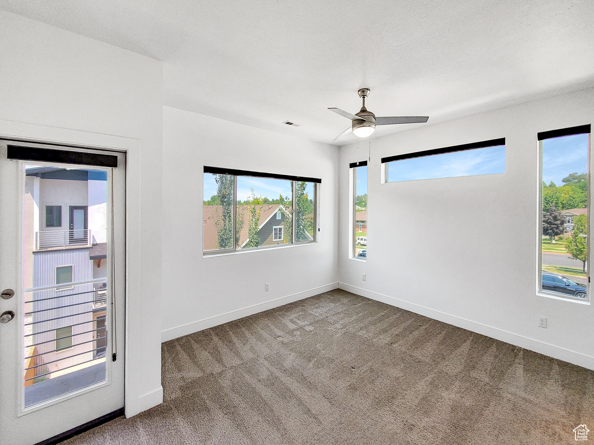 Carpeted spare room featuring ceiling fan and a healthy amount of sunlight