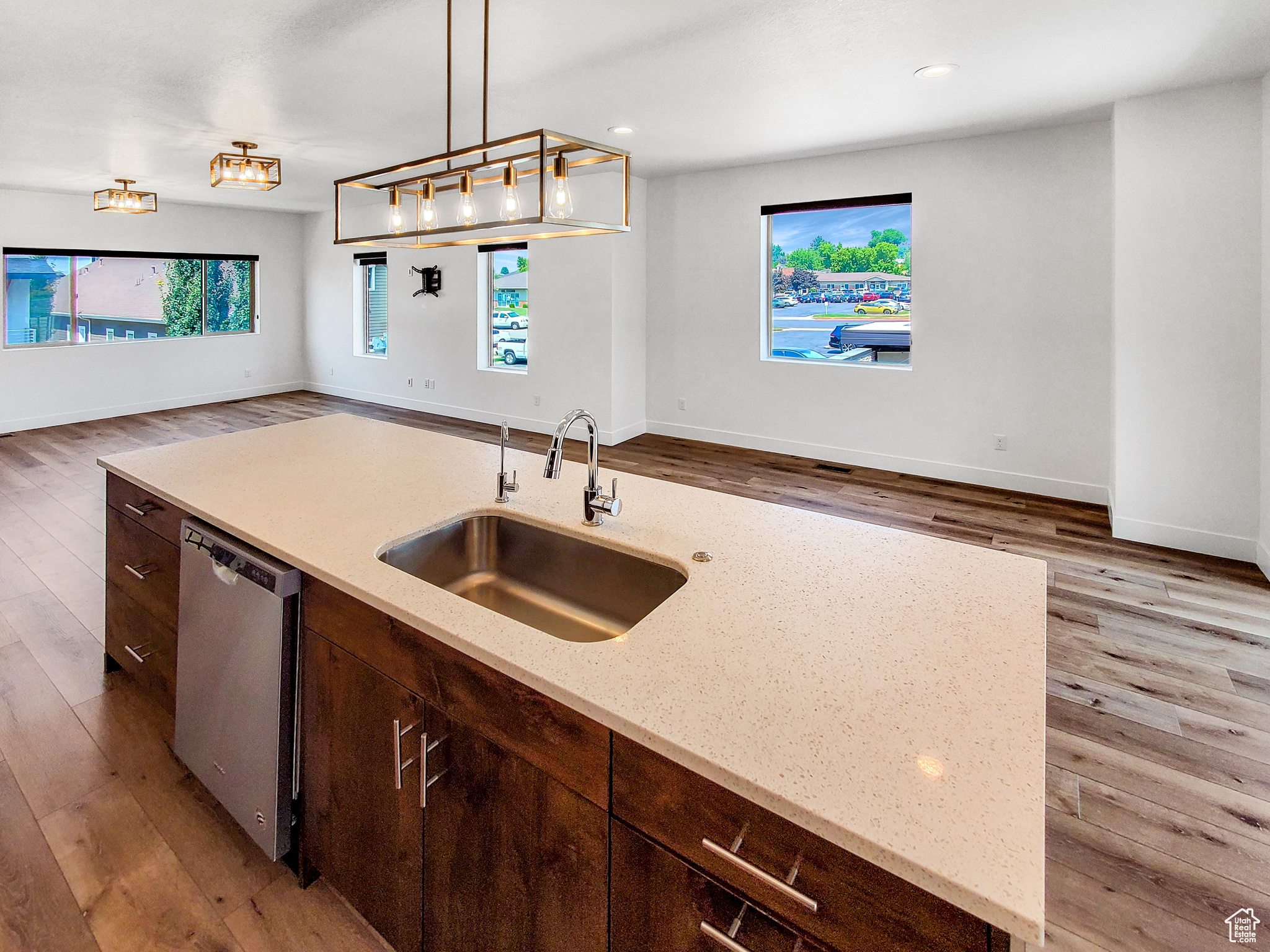 Kitchen with dishwasher, a healthy amount of sunlight, hardwood / wood-style floors, and decorative light fixtures