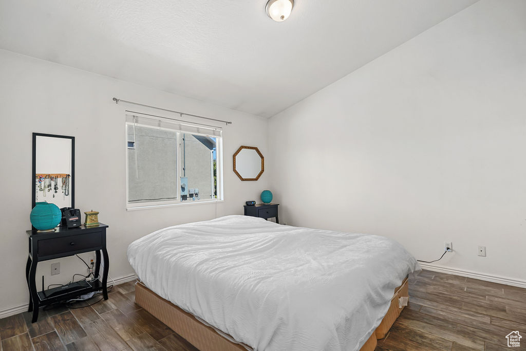 Bedroom with dark hardwood / wood-style flooring and vaulted ceiling