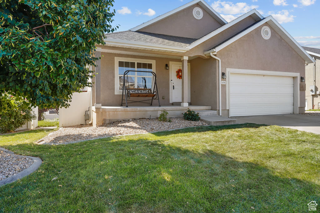 View of front facade featuring a front lawn, a garage, and covered porch