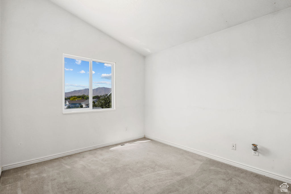 Carpeted spare room with lofted ceiling