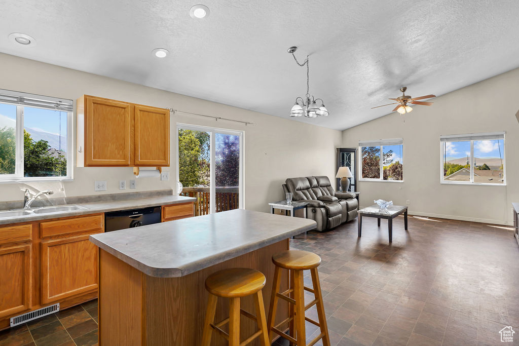 Kitchen featuring a center island, decorative light fixtures, sink, lofted ceiling, and a kitchen breakfast bar