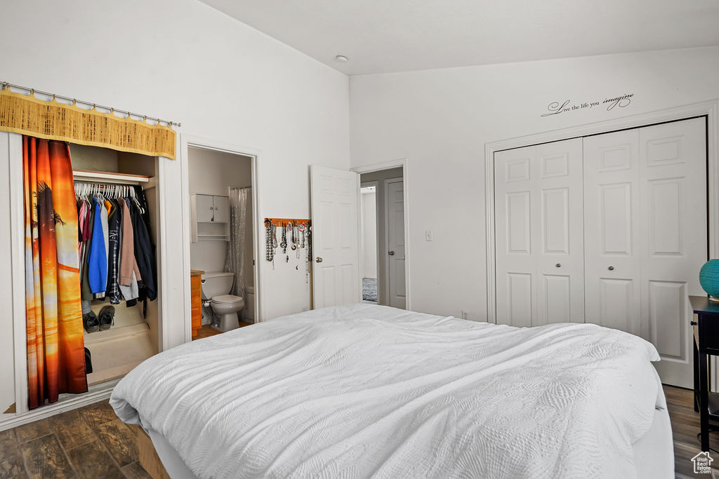 Bedroom with two closets, dark hardwood / wood-style floors, ensuite bathroom, and vaulted ceiling