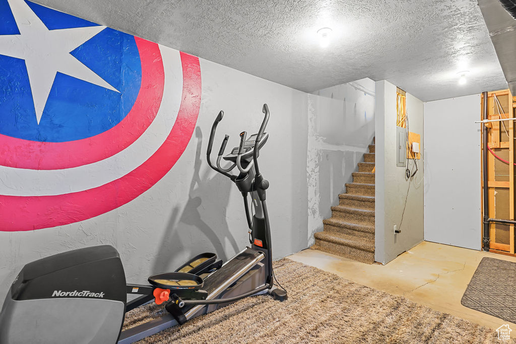 Workout area featuring a textured ceiling and electric panel