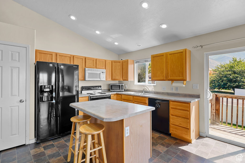 Kitchen with black appliances, a center island, sink, a breakfast bar, and lofted ceiling