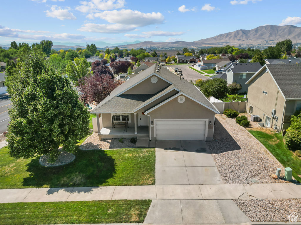 View of front of house featuring a mountain view, a front yard, and a garage