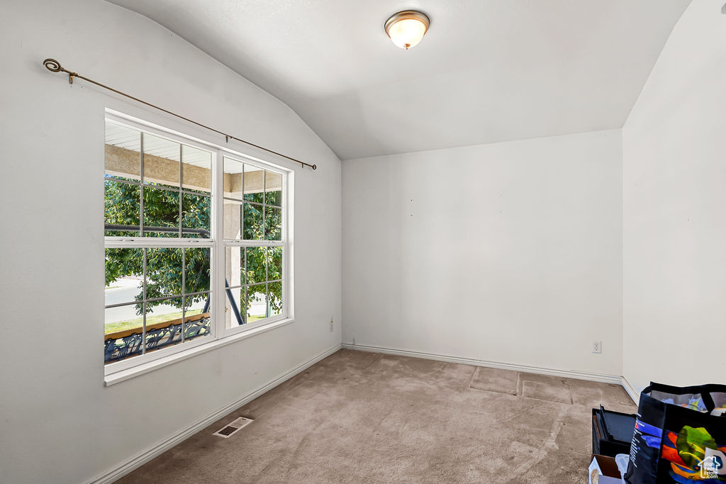 Carpeted spare room featuring lofted ceiling