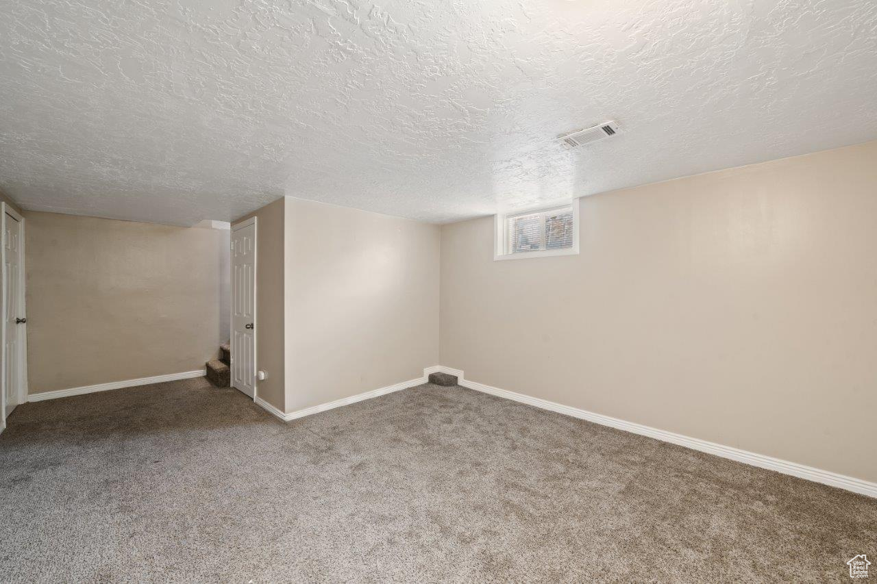 Basement featuring a textured ceiling and carpet floors