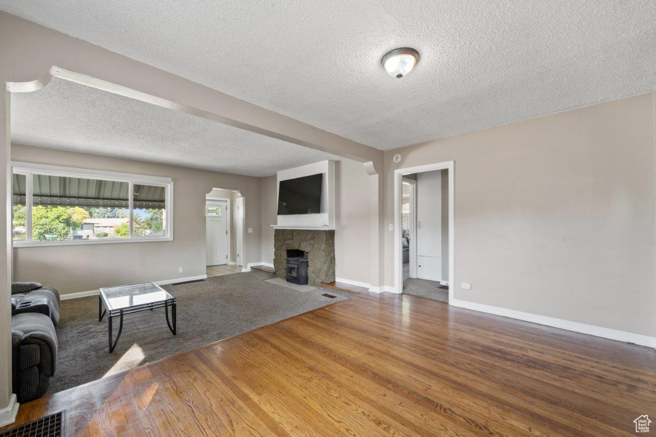 Unfurnished living room with a textured ceiling, a tile fireplace, and hardwood / wood-style flooring